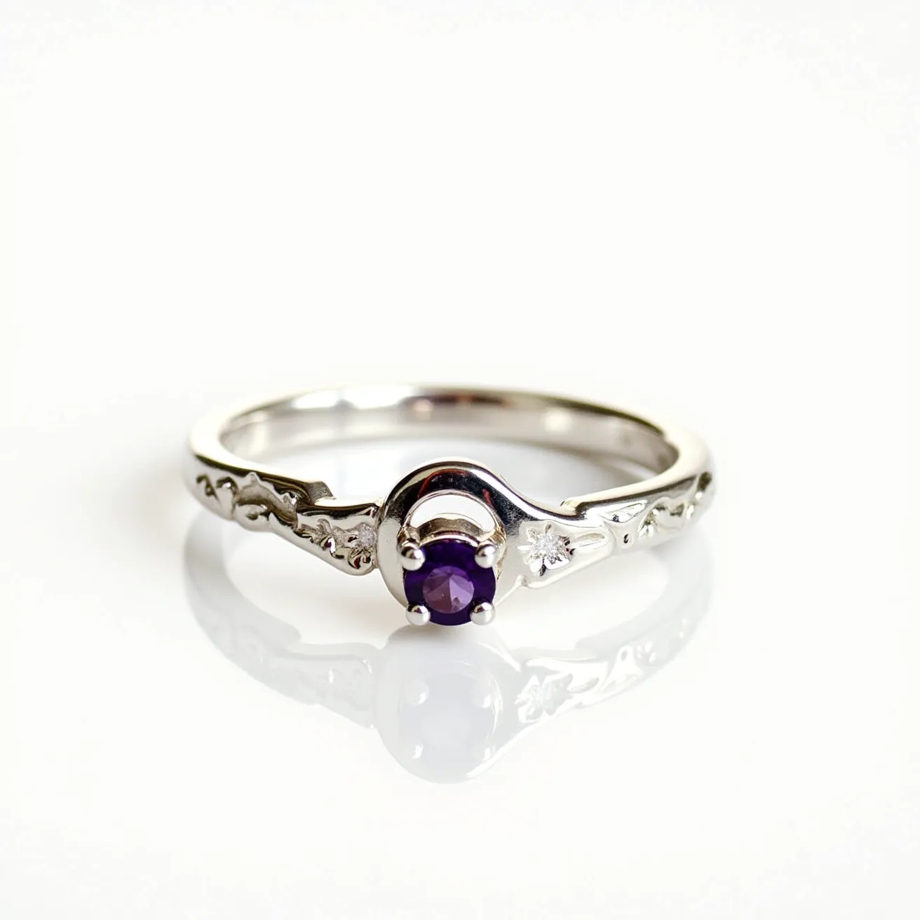 This amethyst promise ring features a prominent round-cut amethyst set in a classic prong setting. The band is crafted from a polished metal, likely silver or white gold, with intricate detailing resembling floral or artistic patterns that enhance its elegance. Flanking the central amethyst are small, round accent stones, possibly diamonds or cubic zirconia, which add a touch of sparkle. The band completes with a graceful curve, and the design harmonizes beautifully for a timeless and meaningful accessory.