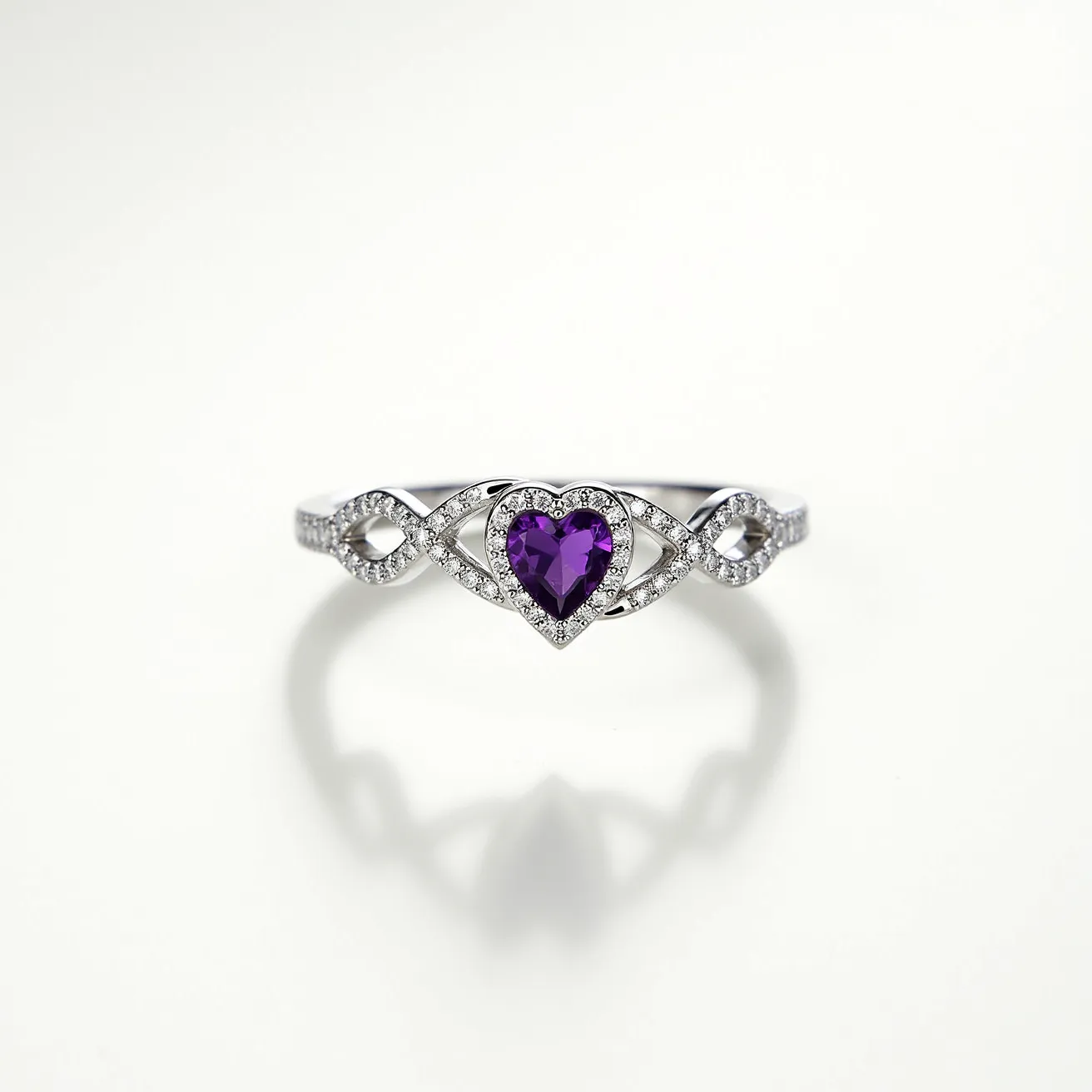 This amethyst promise ring features a stunning heart-shaped amethyst as its centerpiece, showcasing a brilliant purple hue. The gemstone is set in a delicate prong setting, allowing maximum exposure to light and enhancing its natural sparkle. Surrounding the amethyst are intricate loops and swirls meticulously encrusted with small, clear gemstones, likely cubic zirconia or diamonds, which add a beautiful contrast and additional brilliance to the piece. The band appears to be crafted from a polished white metal, possibly sterling silver or white gold, which complements the overall elegant design and provides durability.