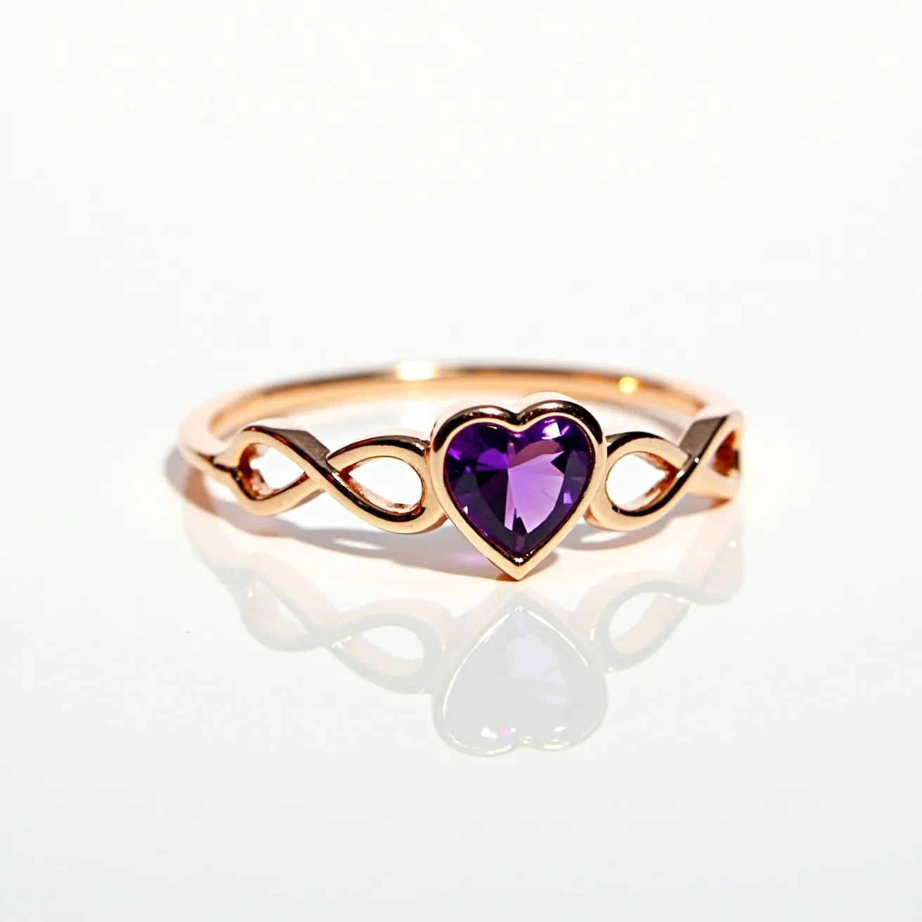 This amethyst promise ring features a heart-shaped amethyst gemstone as its centerpiece, beautifully capturing attention with its rich purple hue. The gem is set in a rose gold band, which adds a warm and romantic touch. The band includes an elegant infinity design on either side of the gem, symbolizing eternal love and commitment. The amethyst is securely held in a simple bezel setting, which provides a smooth and modern finish while protecting the stone. This ring combines timeless elegance with meaningful symbolism, making it a precious gift for a loved one.