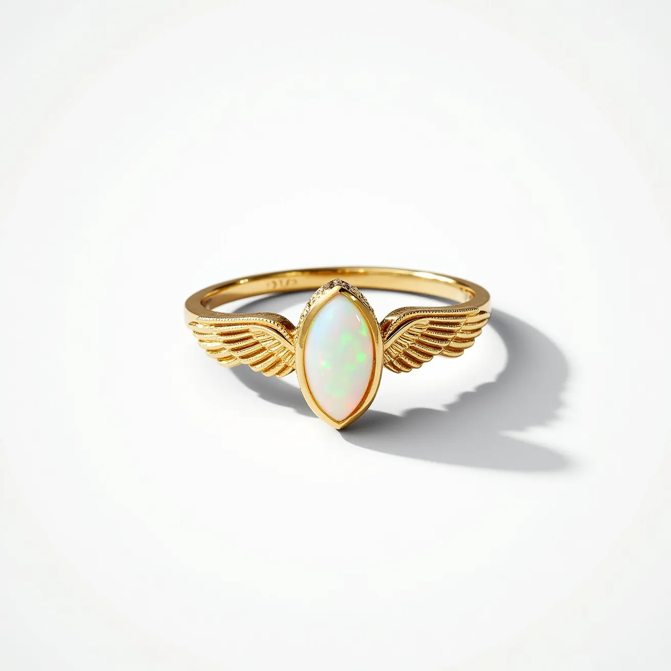 This angel ring features a gold band delicately crafted into a graceful design resembling angel wings. At the center, it showcases an opal stone cut into a marquise shape, secured in a bezel setting that enhances its iridescent qualities. The ring is smooth and polished, highlighting the lustrous quality of the gold and the vibrant play-of-color in the opal.