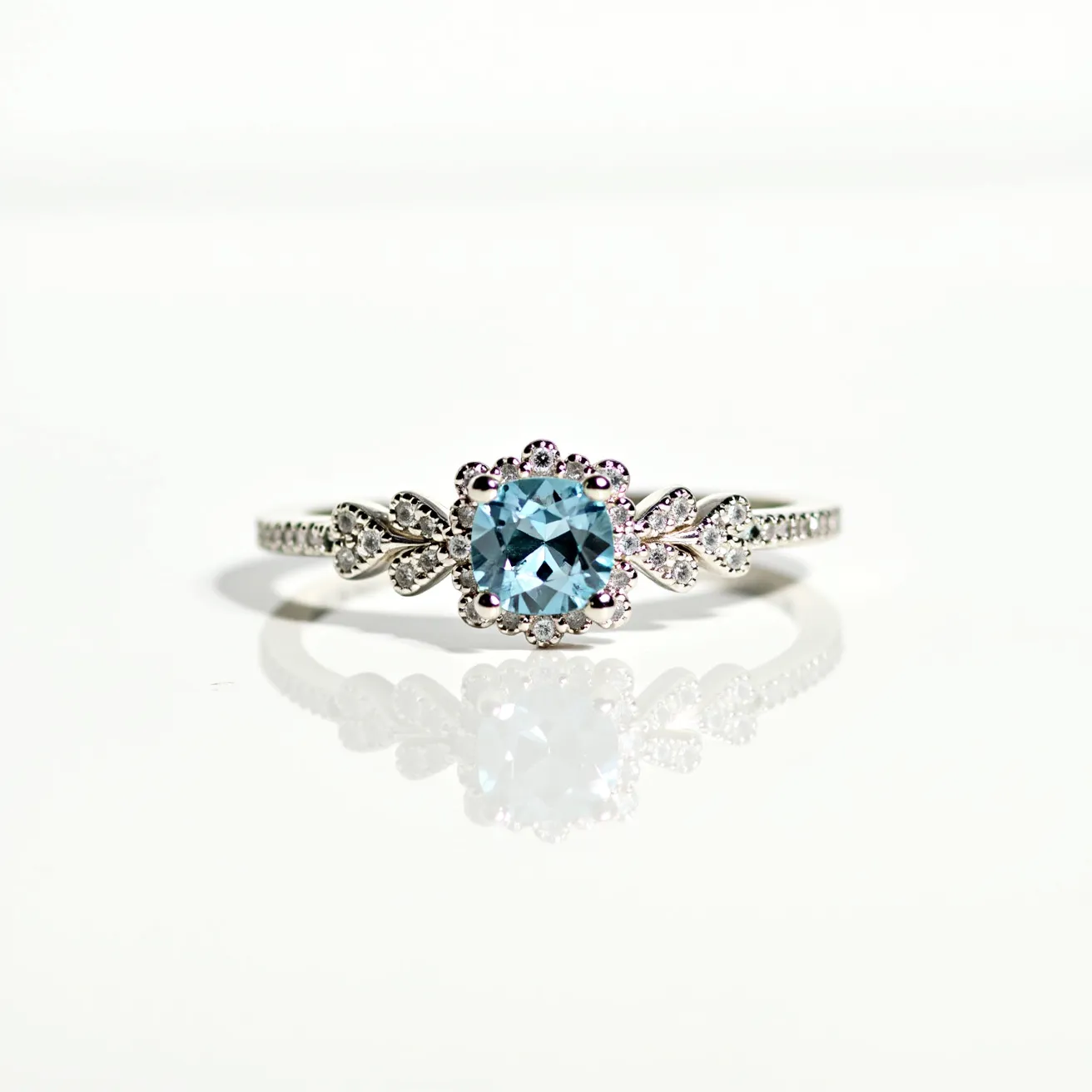 This aquamarine ring features a stunning central aquamarine gemstone, cut into a brilliant shape that enhances its natural sparkle and radiance. The aquamarine is held securely in a decorative setting that resembles a flower with intricate detailing, perhaps fashioned from sterling silver or white gold, contributing to the ring's elegant and sophisticated appearance. On each side of the aquamarine, there are delicate floral motifs adorned with smaller stones, likely diamonds or cubic zirconia, which add an additional layer of brilliance and visual interest to the piece. The band itself continues the theme of elegance with finely set stones along its surface, completing the ring’s luxurious design.