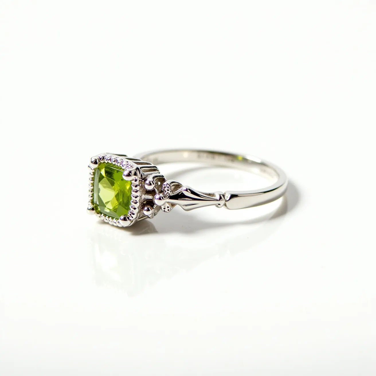 This august birthstone ring features a stunning peridot stone, known for its vibrant green hue, set in a sophisticated silver band. The peridot is cut in a square shape, enhancing its natural brilliance and clarity. It is secured with a decorative bezel setting, which is adorned with small, intricate metalwork details that add elegance to the overall design. The band's shank is smooth and polished, ensuring a comfortable and stylish fit. This exquisite piece is perfect for those celebrating an August birthday or anyone drawn to the unique charm of peridot.