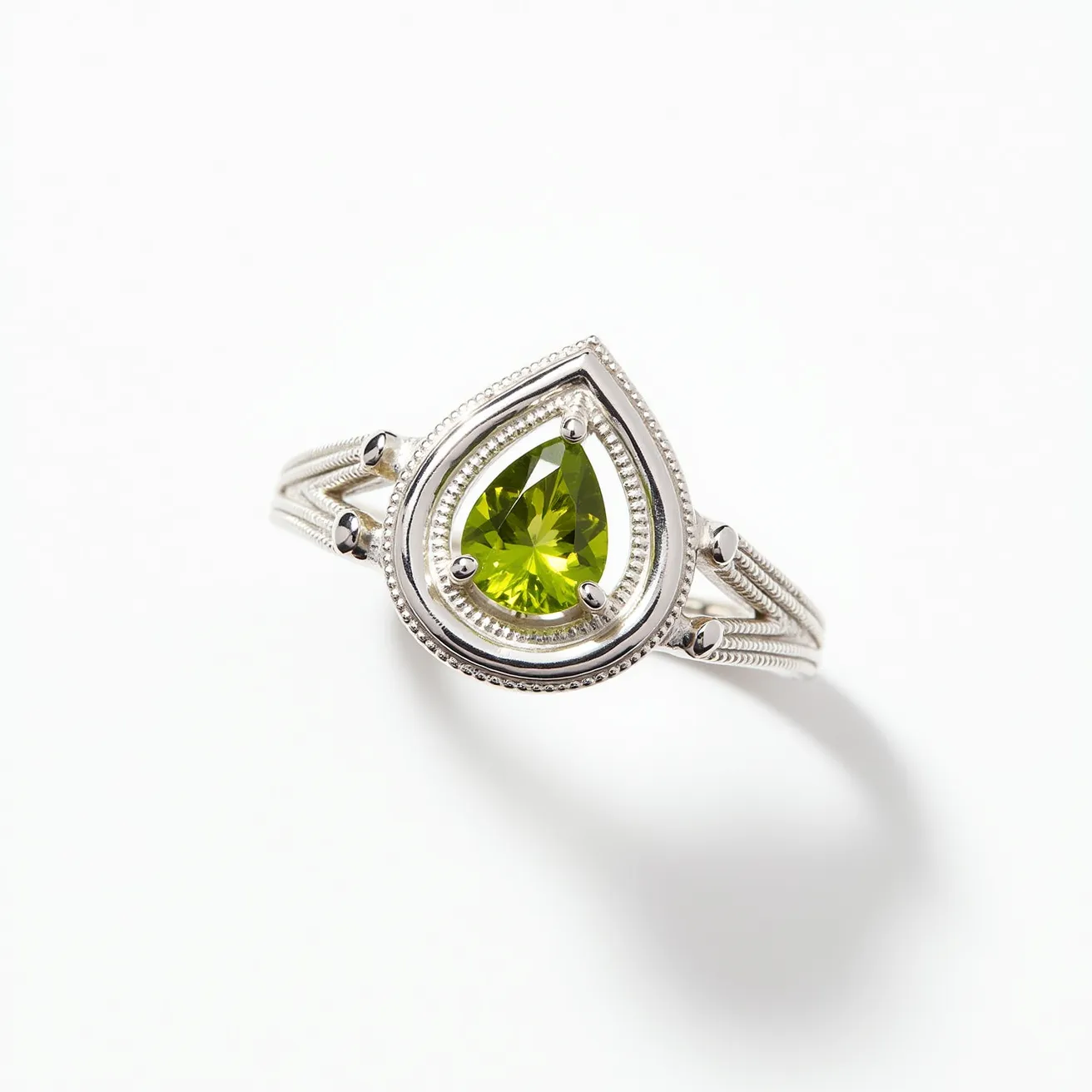 This August birthstone ring features a prominent pear-shaped peridot gemstone, set elegantly in a prong setting. The peridot, known for its vivid green hue, serves as the centerpiece, its facets expertly cut to enhance light reflection. The gemstone is encircled by a detailed silver band, showcasing intricate detailing that adds texture and depth to the ensemble. The ring band is ornately crafted, suggesting a blend of classic and modern design elements, and is likely made of sterling silver, which complements the peridot's striking color. The overall craftsmanship emphasizes both the beauty of the materials and the symbolic significance of the birthstone.