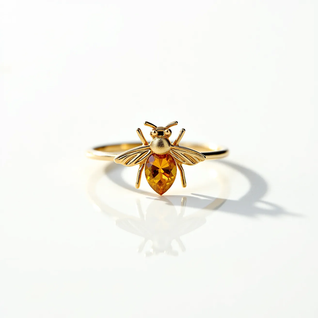 This bee ring features a detailed bee motif crafted from gold-toned metal, showcasing intricate wing and body details. The centerpiece is a pear-shaped yellow gemstone, likely a citrine or yellow topaz, cut to resemble the bee's body and securely held in a bezel setting. The ring has a slim, smooth band without any additional attachments or clasps, emphasizing the bee design as the focal point.