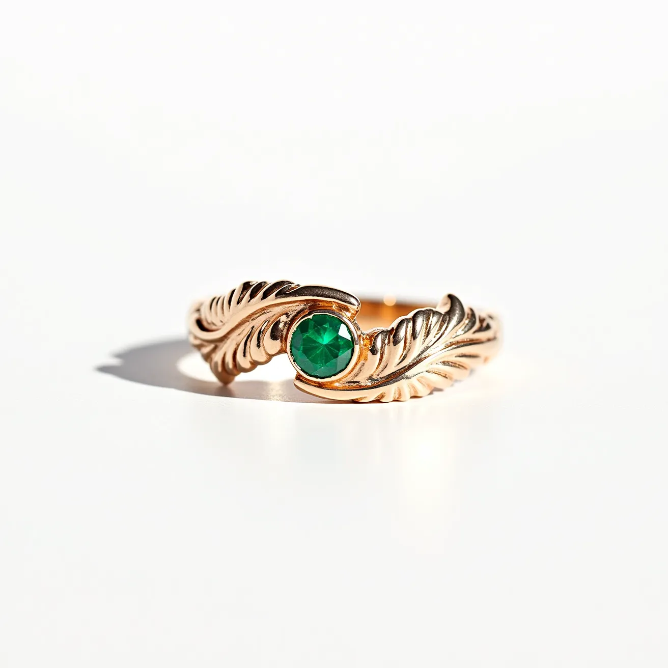 This big ring showcases a luxurious blend of intricately designed gold that forms a textured band resembling feathers. At its center is a vibrant green gemstone, likely an emerald, cut in a round fashion that enhances its brilliance. The stone is securely held in place with a bezel setting that seamlessly integrates with the ornate band design, emphasizing both elegance and durability. The overall craftsmanship of the ring highlights a combination of natural inspiration and refined artistry, making it both a statement piece and a timeless accessory.