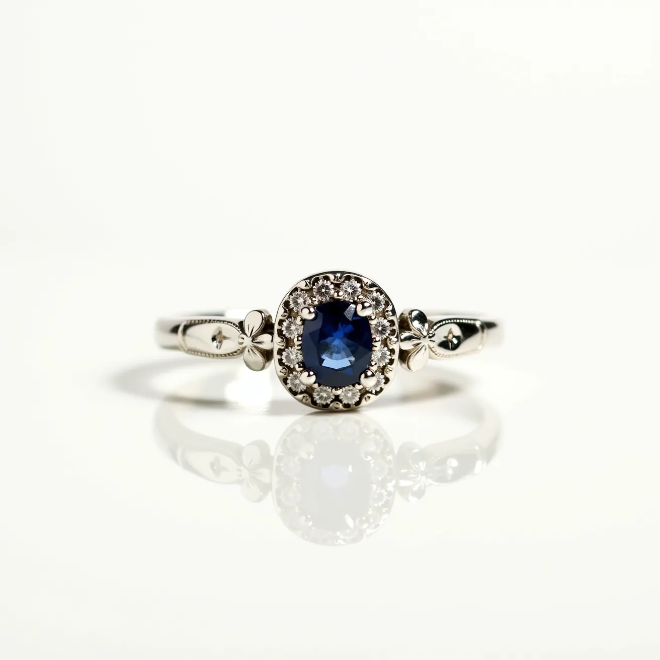 This big ring features a prominent oval-cut blue sapphire set at its center, surrounded by a halo of smaller, round brilliant-cut diamonds. The sapphire is likely prong-set, allowing maximum visibility of the gem, while the diamonds are intricately set to enhance their brilliance. The band appears to be made of a lustrous white metal, possibly white gold or platinum, which complements the cool tones of the sapphire and diamonds. The ring includes delicate decorative elements on the band, adding a touch of elegance and uniqueness to its overall design.