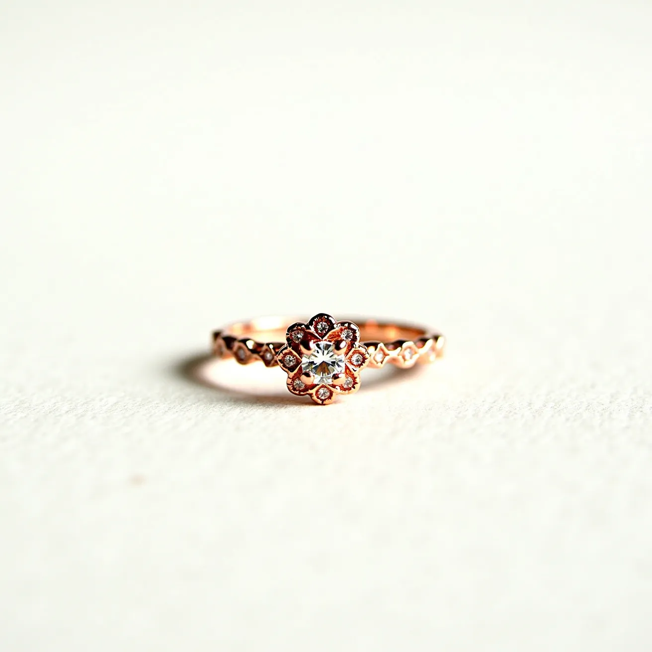 This birthstone ring features a delicate design with what appears to be a rose gold band, skillfully crafted with intricate, symmetrical detailing reminiscent of small floral patterns. At the center, the ring showcases a clear, round-cut gemstone set in a multi-prong setting, which enhances its sparkle and centerpiece allure. The band itself is adorned with small, evenly spaced accents that enhance its visual texture and elegance. The craftsmanship suggests a seamless integration of all components, adding a graceful and sophisticated touch to this charming piece.