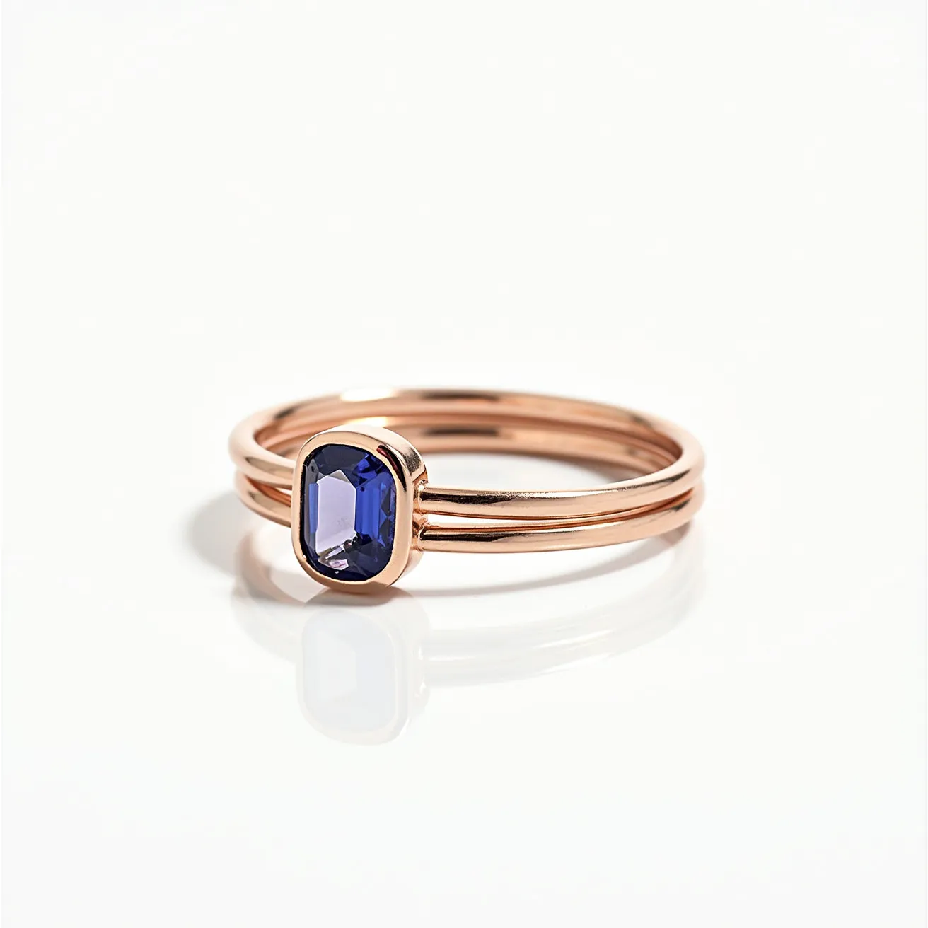 These birthstone stackable rings feature a sleek and polished design crafted from what appears to be a rose gold metal. At the center of one ring is a deep blue gemstone, likely a sapphire, which is cut in an emerald shape and set in a simple bezel setting. The rings are designed to fit together seamlessly, enhancing the elegant and minimalist aesthetic. The lack of additional clasps or attachments allows for easy stacking and versatility.