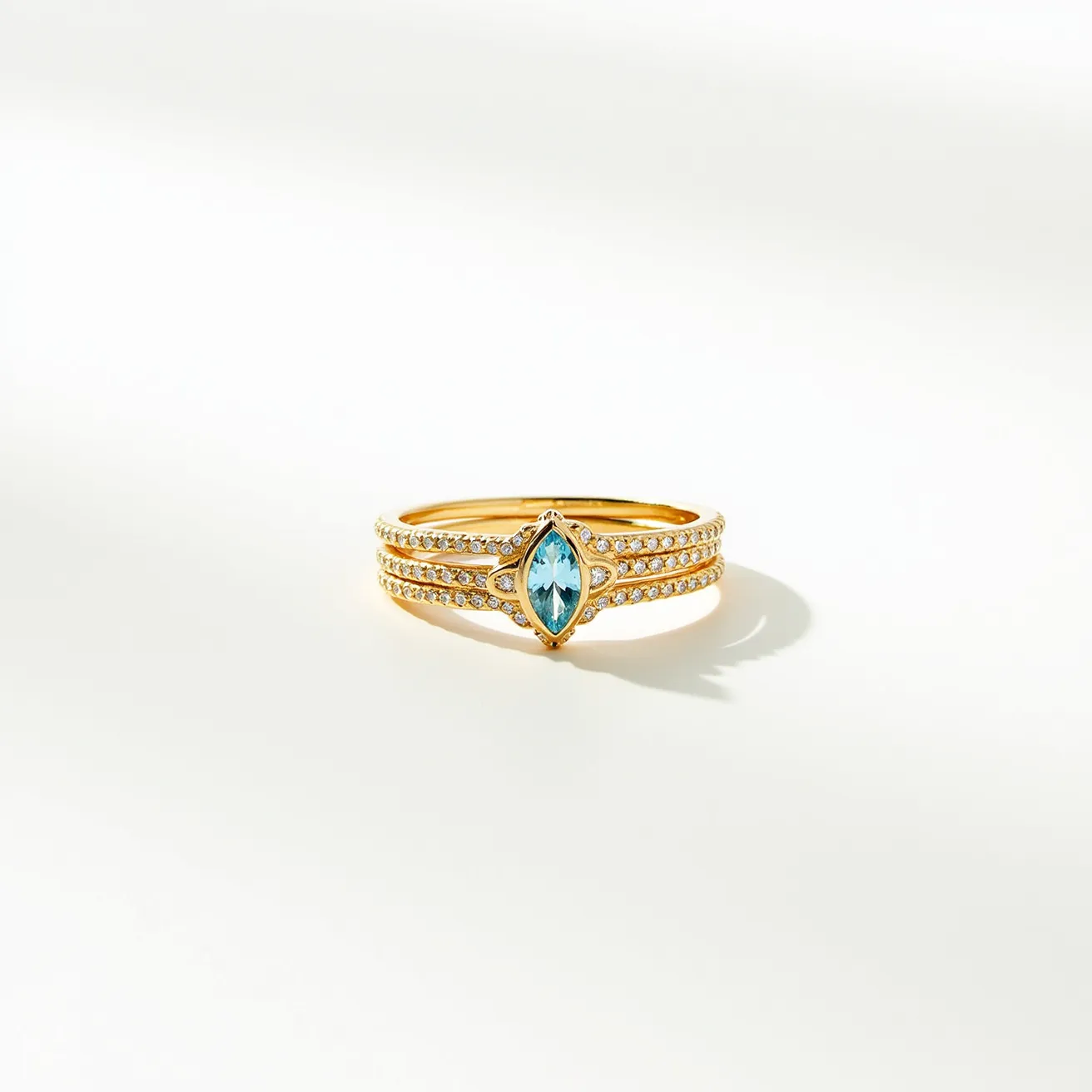 These birthstone stackable rings feature a polished gold band adorned with pavé-set white gemstones, probably diamonds or cubic zirconia, along the band’s outer contour. Centrally set, there is a striking marquise-cut blue gemstone, likely a topaz or aquamarine, cradled in a secure bezel setting that highlights its clarity and vibrant hue. The rings are designed to be worn together seamlessly, without the need for a clasp, allowing for versatile styling, either stacked or worn individually, to complement different looks and preferences.