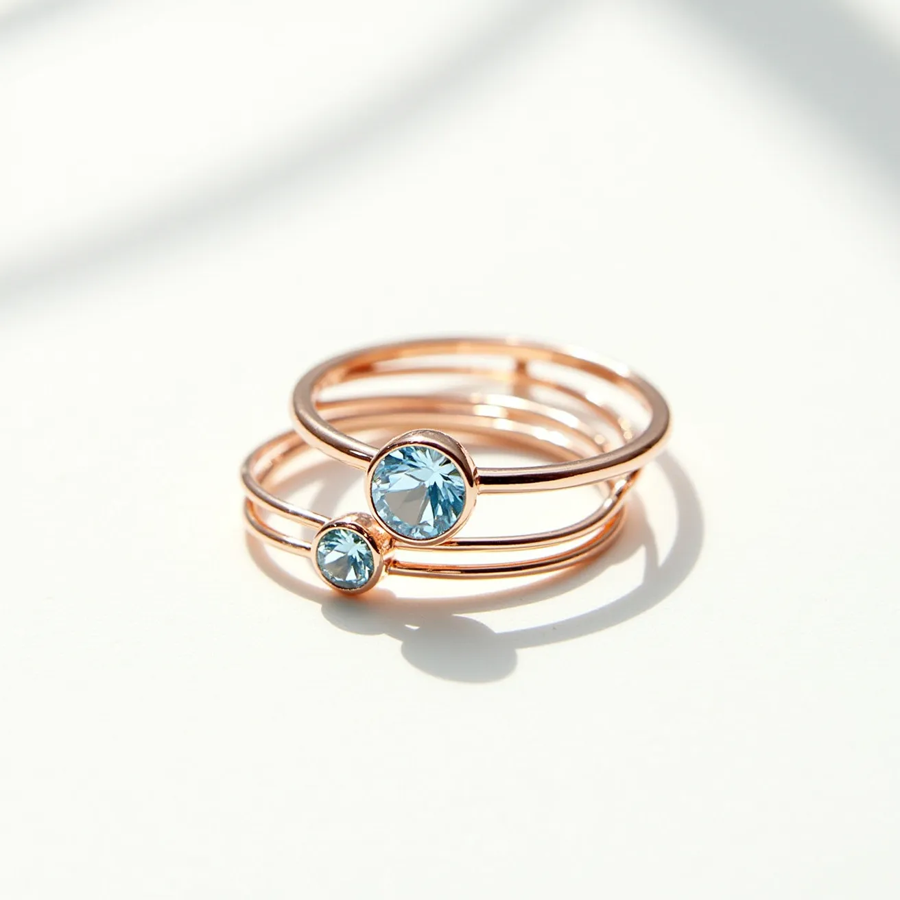 These birthstone stackable rings feature a sleek and contemporary design with slim bands that appear to be made from rose gold. Each ring showcases a round-cut blue gemstone set in a bezel setting, which enhances the elegant and minimalist look. The stones capture attention with their brilliant sparkle, complementing the warm tone of the metal bands. The simplicity in the form of no visible clasp or additional attachment allows the rings to be easily stacked or worn separately, offering versatility in styling.