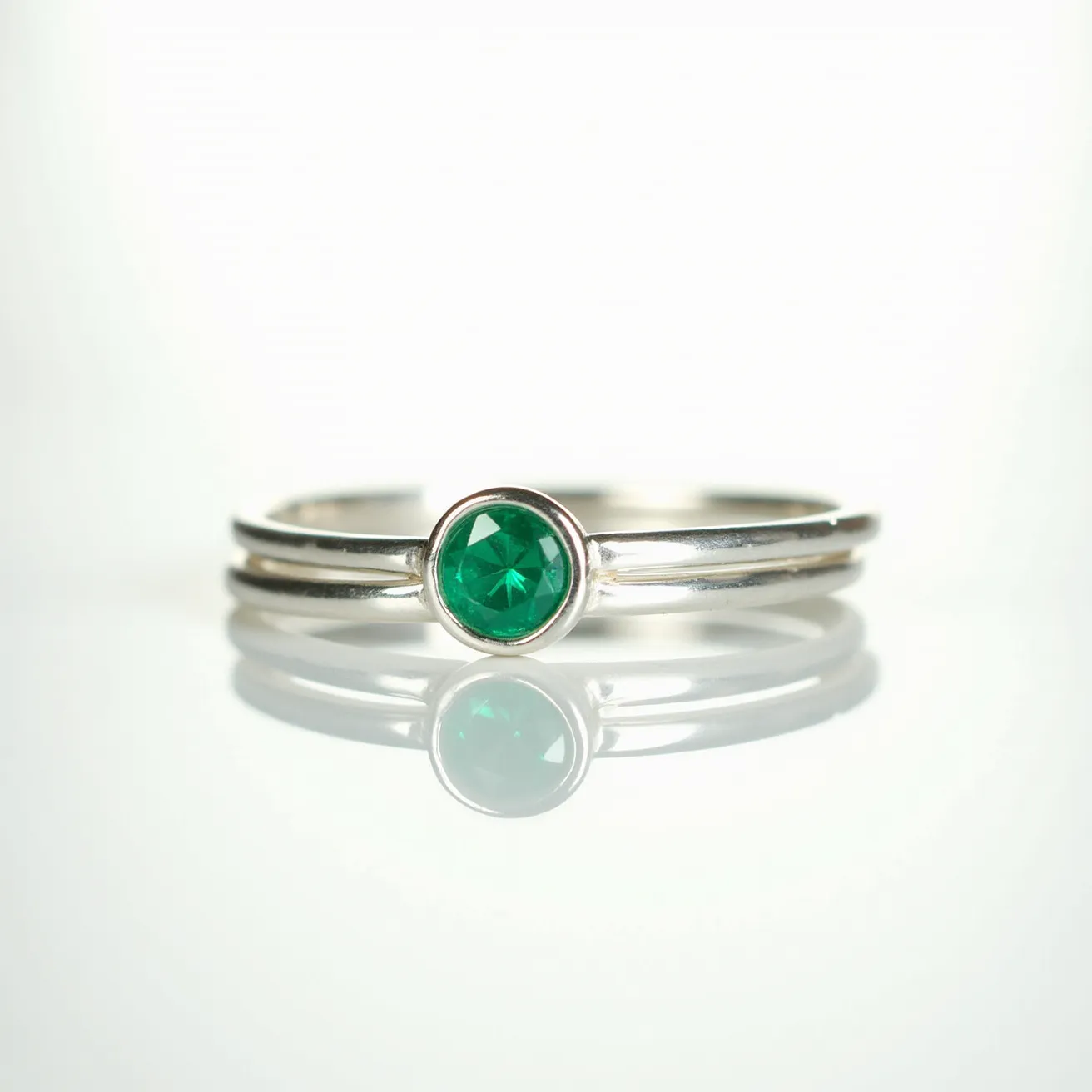 These birthstone stackable rings feature a sleek, minimalist design crafted from silver, forming an elegant band that can be easily layered with others. At the centerpiece is a round-cut, vibrant green gemstone, suggestive of an emerald, associated with the month of May. This gemstone is securely set in a bezel setting, which encases the stone in a smooth, protective metal border, enhancing its brilliance while offering stability. The band is polished, ensuring a smooth finish that complements the vividness of the gemstone, making it an ideal piece for personalization or everyday wear.