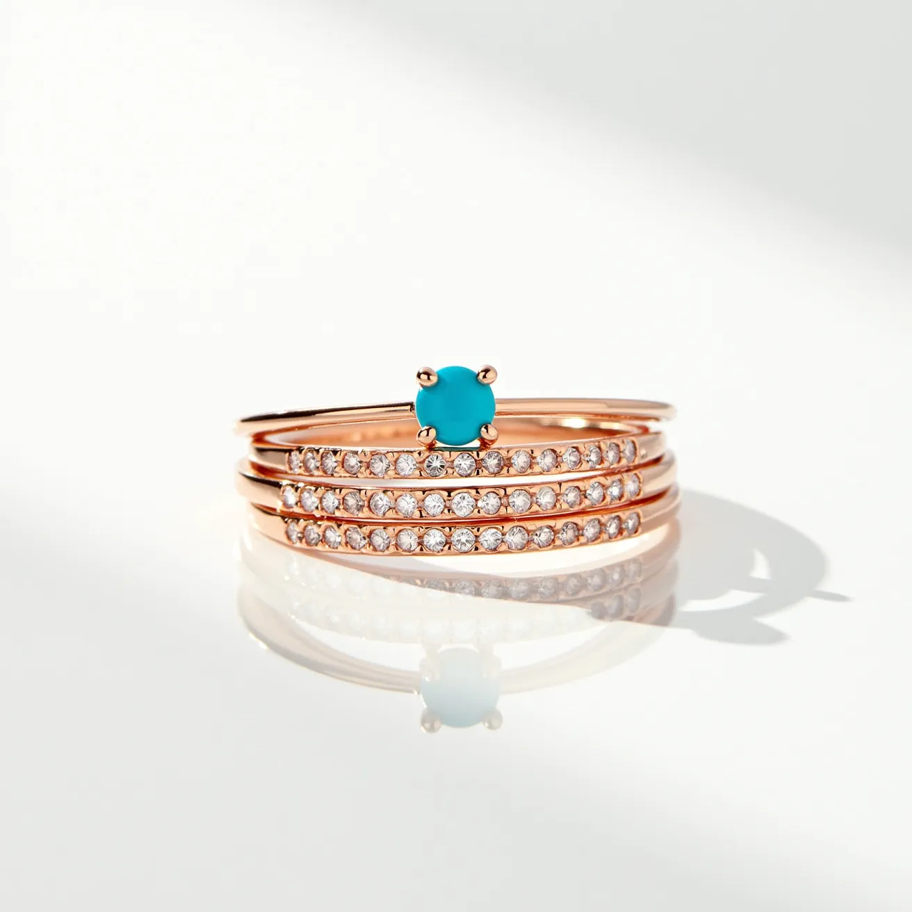 These birthstone stackable rings feature a harmonious blend of elegant materials and intricate design. The rings are crafted from a warm rose gold metal, providing a lustrous and contemporary appeal. At the center, a vibrant turquoise gemstone serves as the focal birthstone, elegantly set in a classic four-prong setting that ensures security and showcases the stone’s brilliance. Surrounding this central ring are additional bands embellished with a series of small, round-cut clear stones, meticulously set in pave style to add a touch of sparkle and sophistication. The stackable design offers versatility, allowing the wearer to mix and match according to personal style and preference.