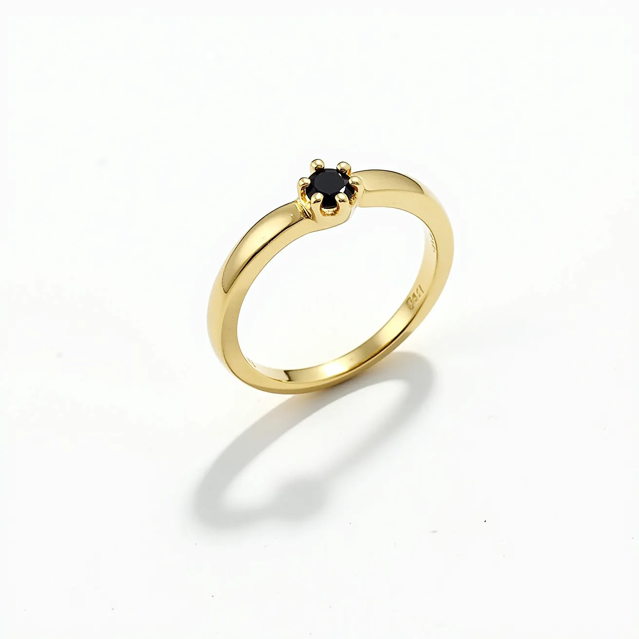 This black diamond ring features a beautifully crafted black diamond set in a solitaire style. The diamond is round cut, showcasing its facets and enhancing its dark, alluring appearance. It is securely held in place by a prong setting with six claws, maximizing the stone's visibility and sparkle. The band is made of polished yellow gold, which complements the black diamond by providing a striking contrast. The ring's design is elegant and timeless, making it suitable for various occasions.