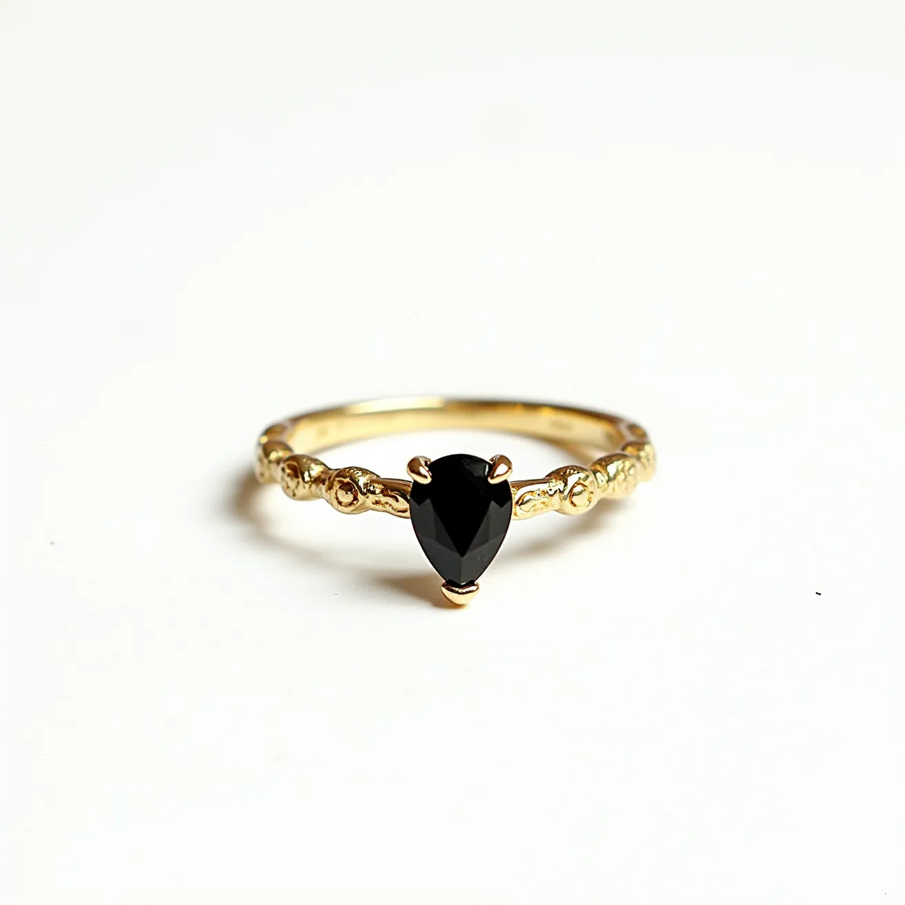 This black diamond ring features a pear-shaped black diamond as the centerpiece, expertly set in a prong setting that secures the gem while highlighting its elegance. The band itself is crafted from gold and is adorned with intricate detailing, adding a touch of sophistication and luxury. The gold enhances the overall allure by providing a striking contrast to the rich, dark hue of the black diamond. The ring's design integrates both classic and contemporary elements, making it a unique and stylish accessory.