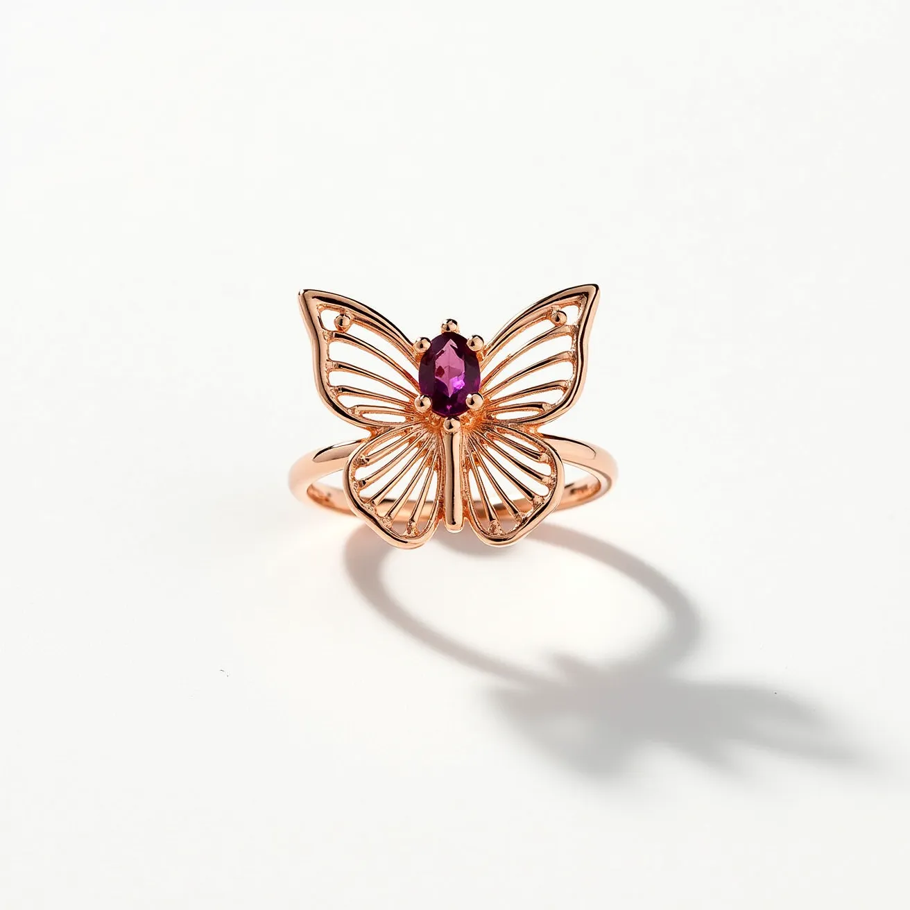 This butterfly ring features an intricate design crafted from rose gold, forming the delicate outline and structure of a butterfly. At its center, a vibrant, oval-cut purple gemstone is securely set, enhancing the ring’s striking appearance. The gemstone is held in place by prongs, ensuring its stability while adding a touch of elegance. The ring exhibits a smooth, polished finish, emphasizing the luxurious material and craftsmanship involved in its creation. The band, also made of rose gold, seamlessly integrates with the butterfly motif, providing a cohesive and stylish look.