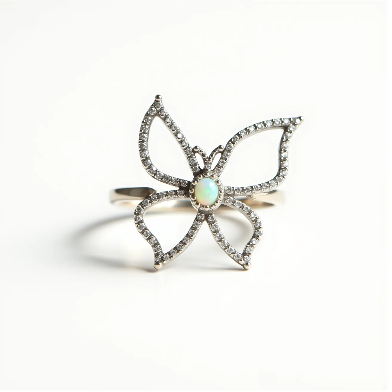 This butterfly ring showcases an intricate openwork design, formed from what appears to be sterling silver or white gold. Each wing is adorned with a sequence of small, round-cut diamonds, meticulously set in a pavé setting, lending a sparkling allure. At the center of the butterfly, a captivating round opal takes prominence, set in a bezel setting that highlights its iridescent hues. The band of the ring is simple yet elegant, seamlessly holding the detailed butterfly motif without a visible clasp, emphasizing the design's continuity and sophistication.