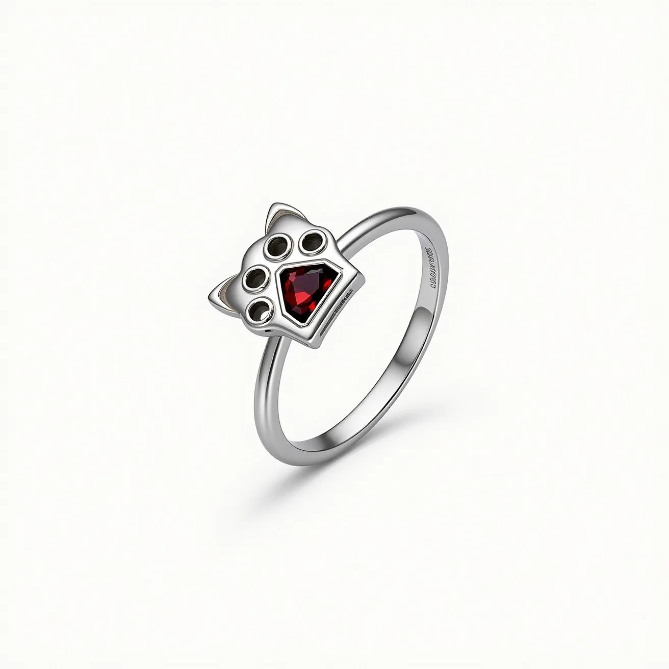 This cat ring features a sleek, metallic band, likely made from silver or a similar material, offering a polished and modern look. The standout element is the cat-shaped top, which incorporates a central, deep red, gem resembling a heart cut, securely set in a bezel setting. The surrounding elements mimic the facial features of a cat, with small circular accents that enhance the design's whimsical charm. The ring appears to have no additional clasps or attachments, emphasizing its simplicity and elegance.