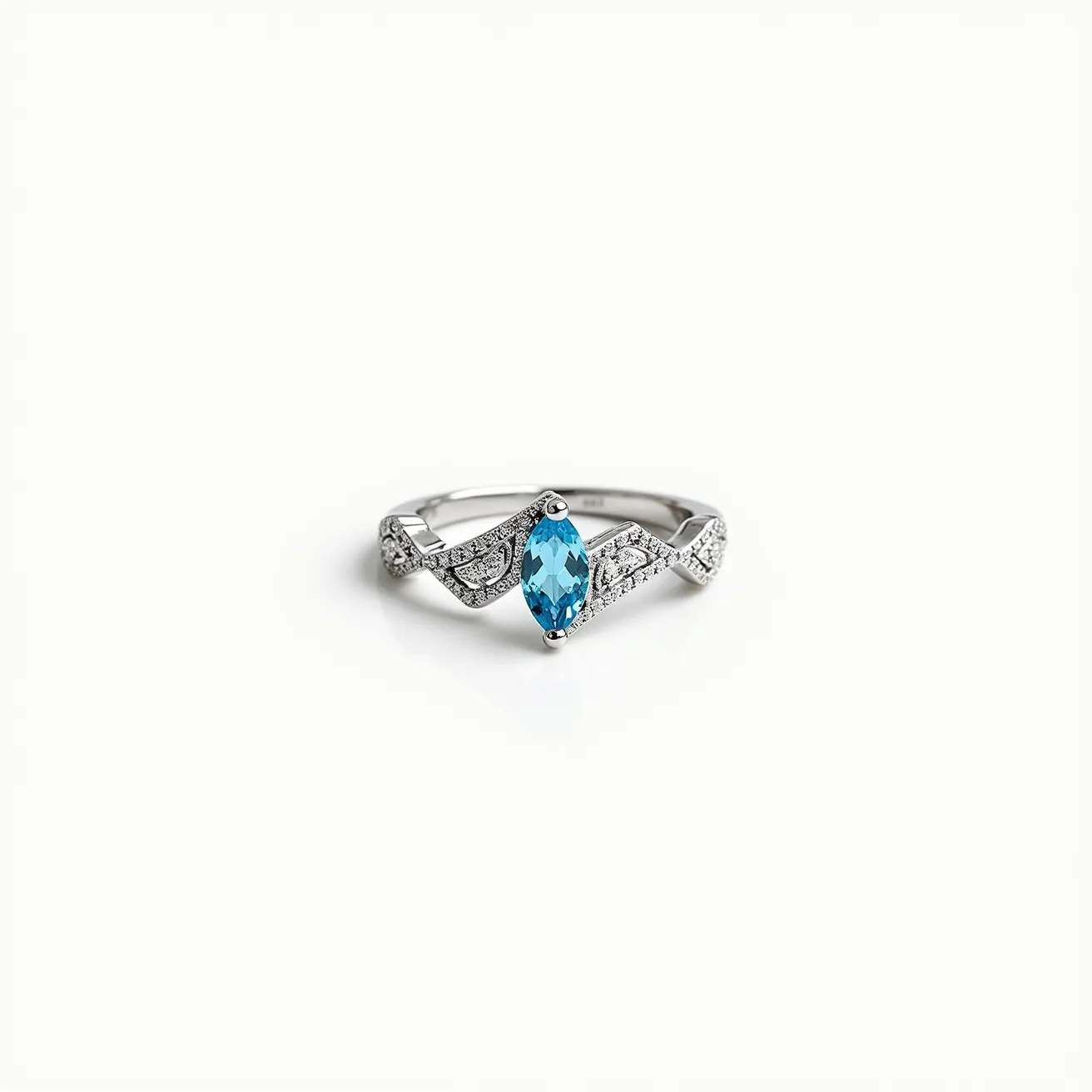 This chevron ring features a sleek, polished band of metal, likely silver or white gold, forming a distinctive v-shaped design. At its center, a marquise-cut blue gemstone is elegantly set, adding a vibrant splash of color. The stone is secured with prongs, which are integral to showcasing the cut and clarity of the gemstone. Flanking the central stone, the band is adorned with smaller, clear stones, possibly diamonds or cubic zirconia, in a pavé setting, enhancing its sparkle and luxurious appearance. The overall design is both modern and timeless, emphasizing elegance and refinement.