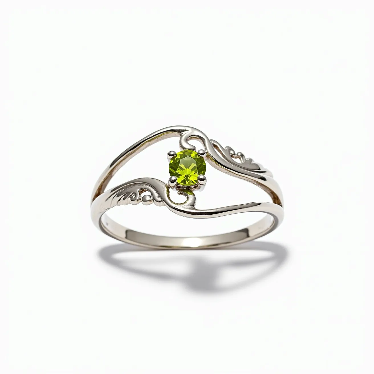 This chevron ring features an elegant design crafted from polished silver, showcasing a vibrant green peridot gemstone at its center. The peridot is round-cut, held securely in place with a classic four-prong setting, which enhances its brilliance and allows light to pass through. The band gracefully curves around the gemstone, incorporating delicate, flowing decorative elements that accentuate the chevron shape. These ornamental scrolls add a touch of sophistication, seamlessly blending with the overall design to create a harmonious, eye-catching piece.