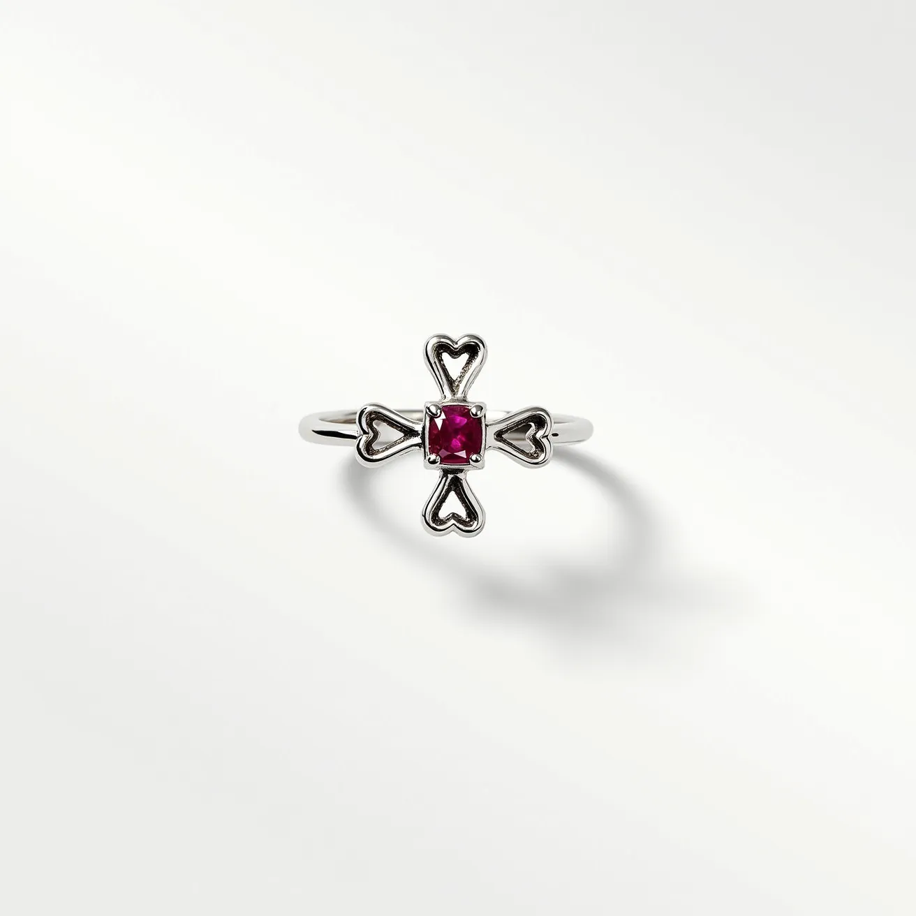 This chrome hearts ring showcases a distinctive design featuring a central, square-cut gemstone with a vibrant red hue, likely set in a prong setting to secure the stone prominently. The ring is crafted from a likely sterling silver material, giving it a polished and sophisticated finish. The design is further accentuated with heart-shaped motifs extending symmetrically from the center stone in a cross-like pattern, adding a unique, artistic dimension to the piece. There are no additional clasps or attachments, underscoring its simplicity and elegance in the craftsmanship.