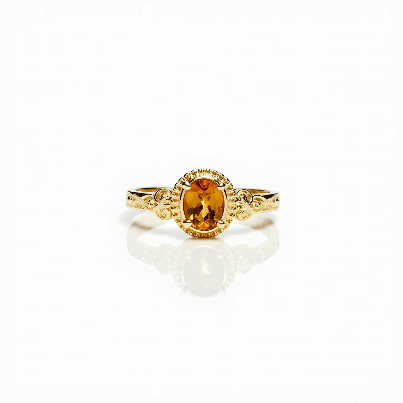 This citrine ring features a radiant, oval-cut citrine gemstone set prominently in the center. The citrine is surrounded by a fine beaded gold bezel that enhances its warm, golden-yellow hue. The band is crafted from gold, which complements the color of the citrine, and showcases intricate detailing on either side of the gemstone, adding an elegant touch to the design. The setting allows the gemstone to be securely held in place, ensuring both stability and display of the stone's natural brilliance.