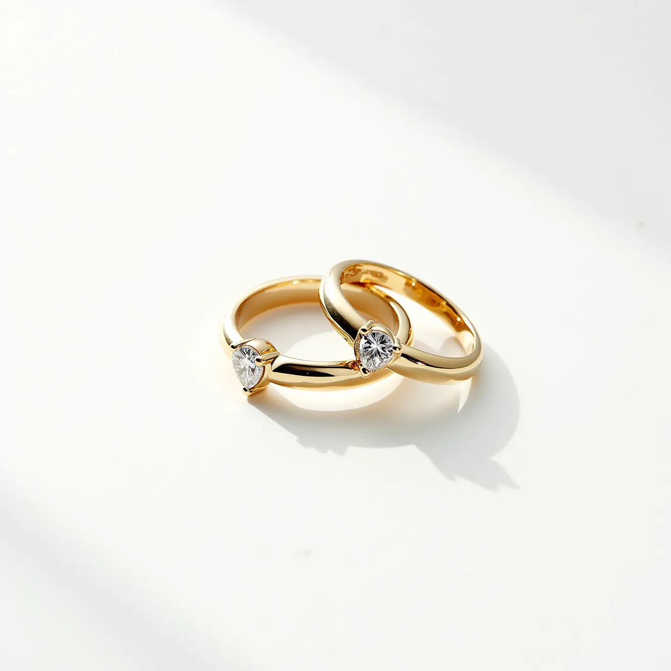 These couple rings appear to be crafted from a high-quality gold material, featuring a polished finish that enhances their elegance. Each ring is adorned with a single brilliant-cut diamond, securely set in a classic prong setting that allows the stone to capture and reflect light. The design is sleek and timeless, with a focus on simplicity and sophistication, making them ideal symbols of commitment and love.