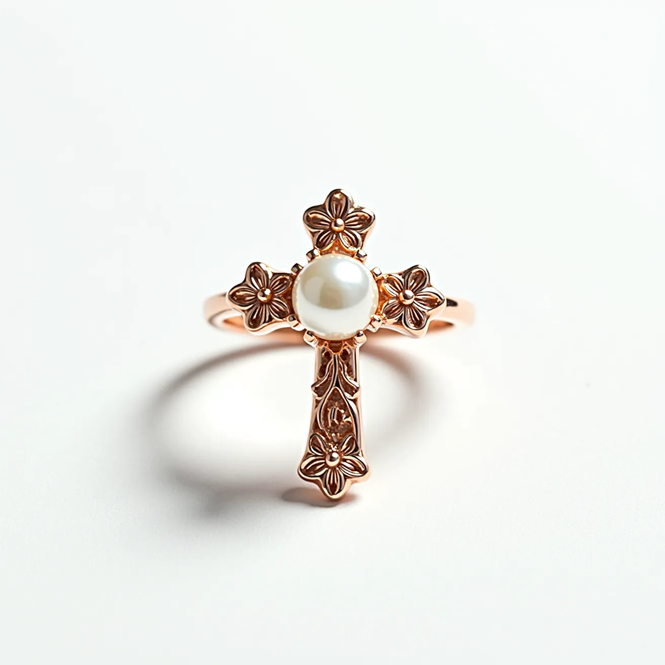 This cross ring features a central pearl set within a delicate floral design, crafted from a warm-toned metal that appears to be rose gold. The cross itself is embellished with intricate floral motifs that add an elegant touch to the overall design. The pearl, with its smooth, rounded surface, is prominently displayed in a bezel setting at the center of the cross, drawing attention to its lustrous quality. The band of the ring is polished, complementing the ornate design of the cross and providing a harmonious balance between simplicity and intricacy.