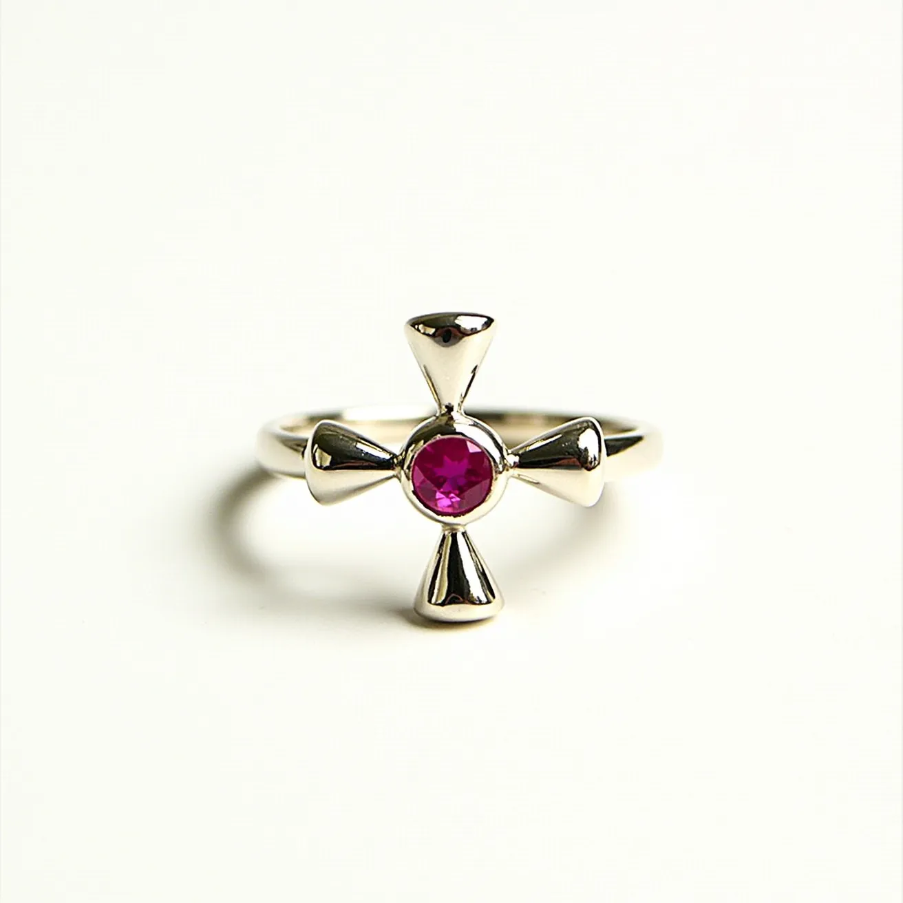 This cross ring is crafted from a polished silver-colored metal, featuring a unique design where the cross forms the central motif. At its heart lies a vibrant pink gemstone, cut in a round shape and set in a bezel setting, which securely holds the stone while allowing its color to be prominently showcased. The metal arms of the cross have a slight taper, adding an elegant touch to the overall design. There is no visible clasp or additional attachment on the band, as the piece is designed as a traditional ring.