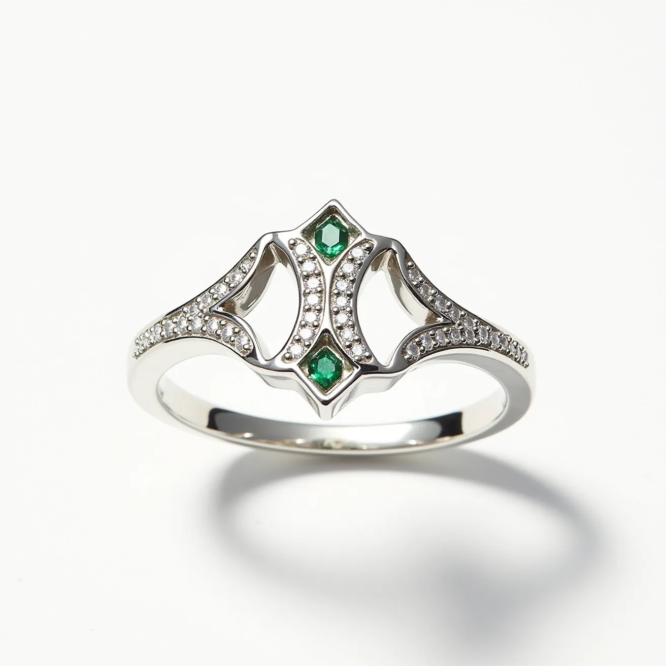 This crown ring features a sleek and elegant design crafted from polished metal, likely white gold or platinum. It is adorned with two vibrant green gemstones, presumably emeralds, cut in a marquise shape. These stones are set centrally in bezels, adding a touch of color and luxury. Surrounding these central stones is a delicate arrangement of small, clear gemstones, possibly diamonds, set in a pave style. The ring's ornate silhouette mimics the contours of a crown, with symmetrical curves and points that create a regal appearance. The band is smooth and continuous, showcasing a seamless integration of design elements without the use of clasps or additional attachments.