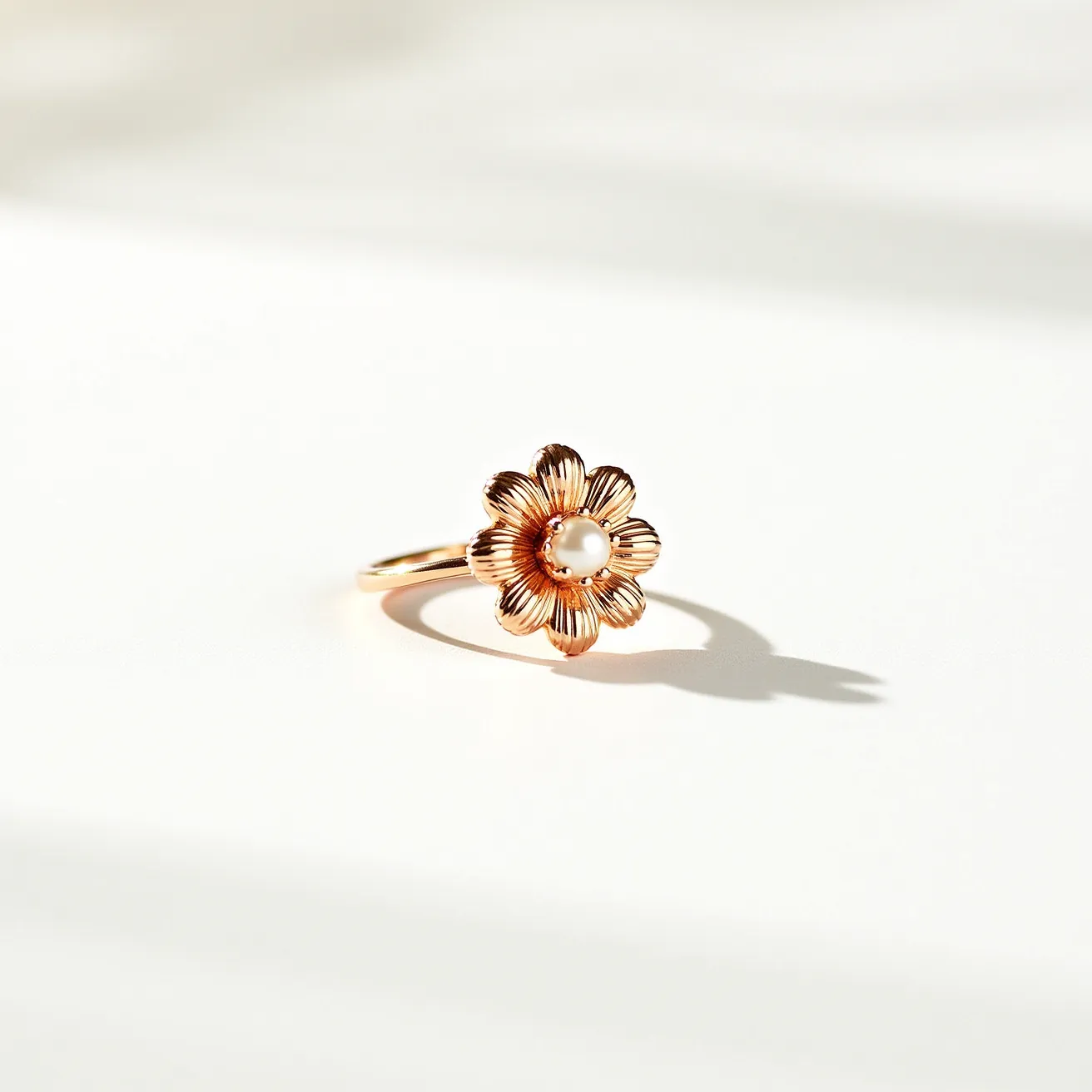 This daisy ring is crafted from a gold-toned material, featuring a flower design with delicately shaped petals. At the center of the daisy is a round pearl, which is securely set to enhance its natural elegance. The band's smooth finish complements the intricate floral details, creating a harmonious and stylish piece that captures the essence of nature-inspired jewelry.