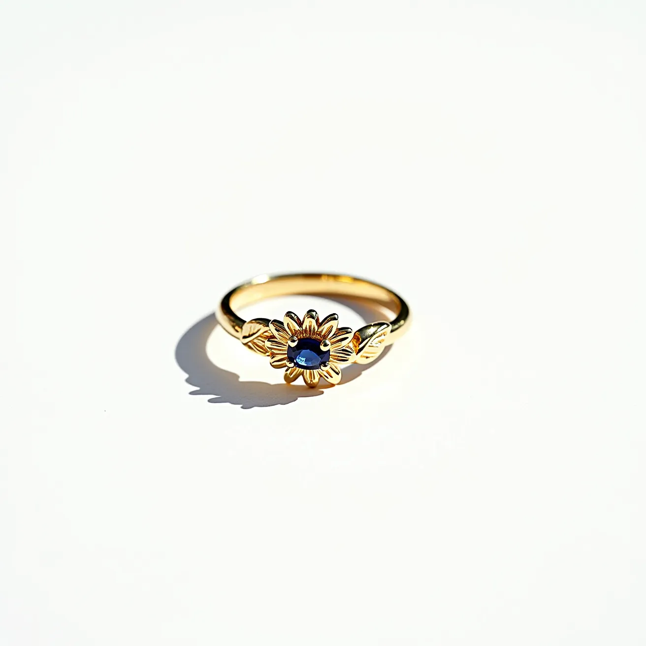 This daisy ring features a beautifully designed gold band that highlights its floral motif. At the center of the daisy is an oval-cut blue gemstone, secured in a prong setting, which adds a striking contrast to the gold petals surrounding it. The band also incorporates delicate leaf designs on either side of the daisy, further enhancing its natural theme. The craftsmanship showcases a blend of simplicity and elegance, making it a charming and unique piece of jewelry.