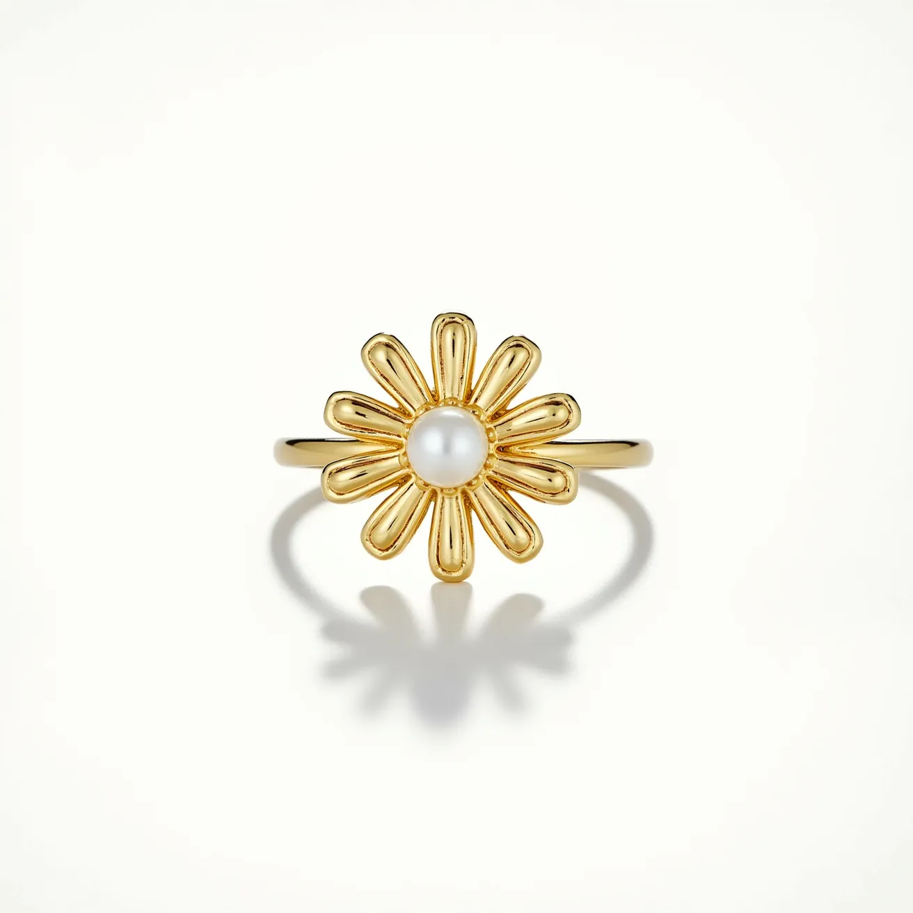 This daisy ring features a delicate design crafted from what appears to be a gold metal, forming petals that surround a central gem. The centerpiece of the ring is a round pearl, set securely in the heart of the daisy, adding a classic and elegant touch. The ring's band is smooth and slender, complementing the floral motif without overpowering it. The pearl is prominently positioned, creating a harmonious balance between the gold petals and the lustrous gem. The overall design emphasizes simplicity and elegance, making it a versatile piece suitable for various occasions.