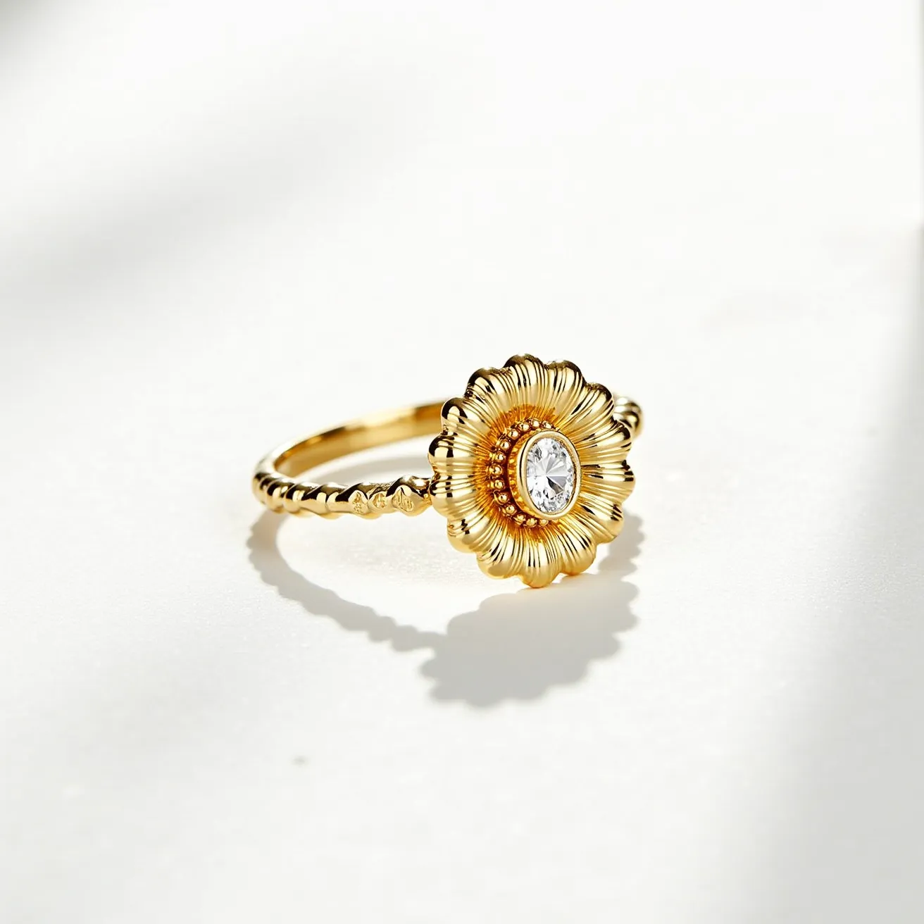 This daisy ring features a beautifully crafted floral design with a rich gold-toned metal forming the petals and band. At the center of the daisy is a clear, oval-cut gemstone, likely a diamond or a cubic zirconia, set securely within a bezel setting that enhances its brilliance. The band itself is delicately detailed with a beaded texture, complementing the intricate design of the daisy motif. The craftsmanship highlights the elegance and timeless appeal of the piece, making it a standout accessory.