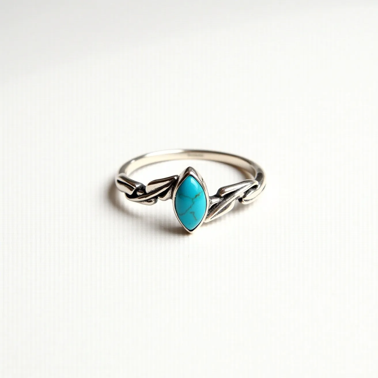 This December birthstone ring is crafted with a sterling silver band that features an elegant, twisted design. At its center, the ring holds a marquise-cut turquoise stone, known for its vibrant blue hue and characteristic veining, securely set in a bezel setting. The intricate pattern of the band complements the gem, enhancing the overall aesthetic appeal. The simplicity of the silver allows the turquoise stone to take the spotlight, making it a perfect piece for those born in December.