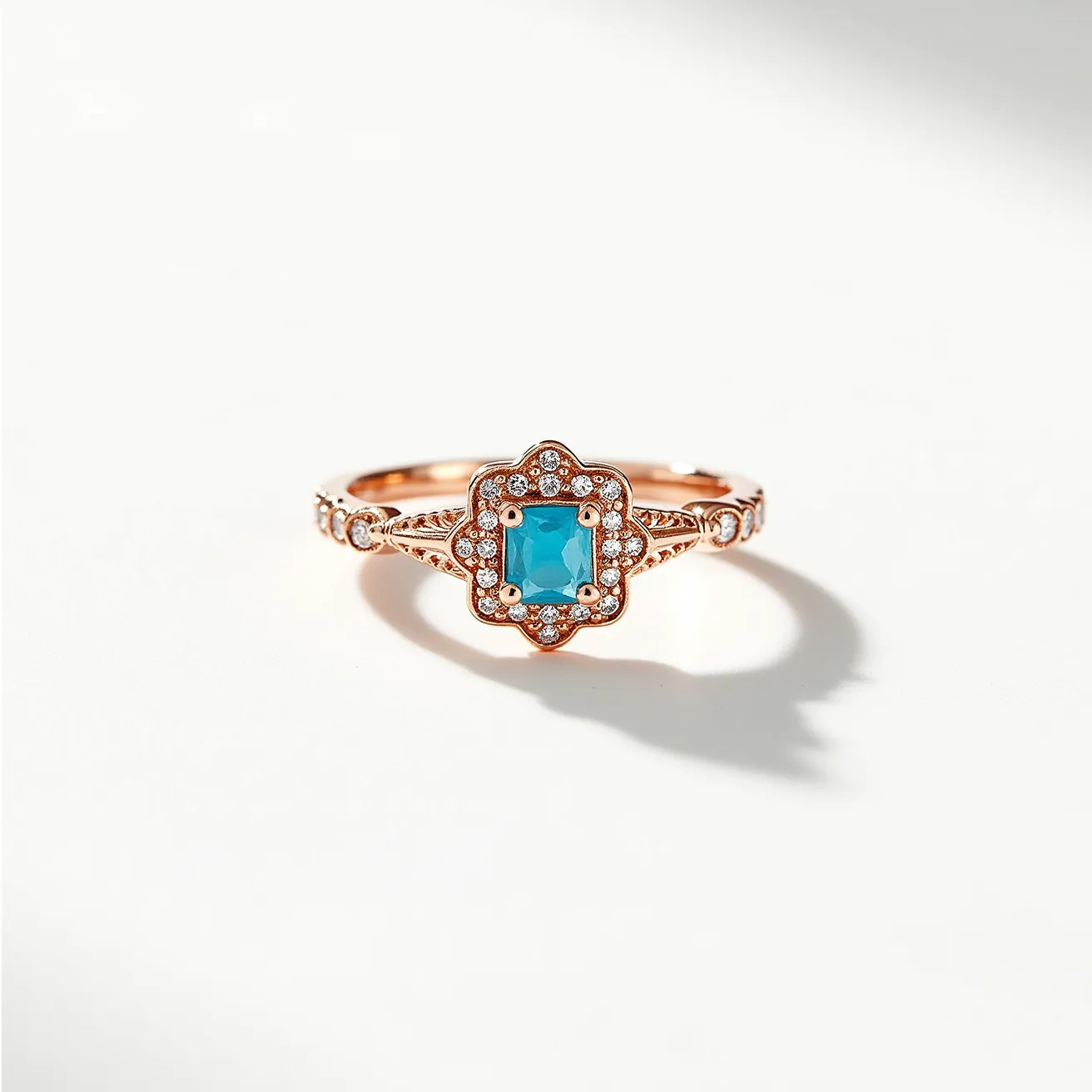 This December birthstone ring features a vibrant blue topaz as its centerpiece, cut in a rectangular shape that is elegantly set within a floral-inspired halo. The surrounding halo showcases small, round, sparkling diamonds that enhance the brilliance of the central stone. The band, crafted in warm rose gold, is intricately detailed with milgrain accents and smaller diamonds embedded in the shoulders, adding to the ring’s sophisticated and ornate design. The overall setting is sophisticated, securely holding the stones while allowing ample light to pass through, accentuating the topaz's natural allure.