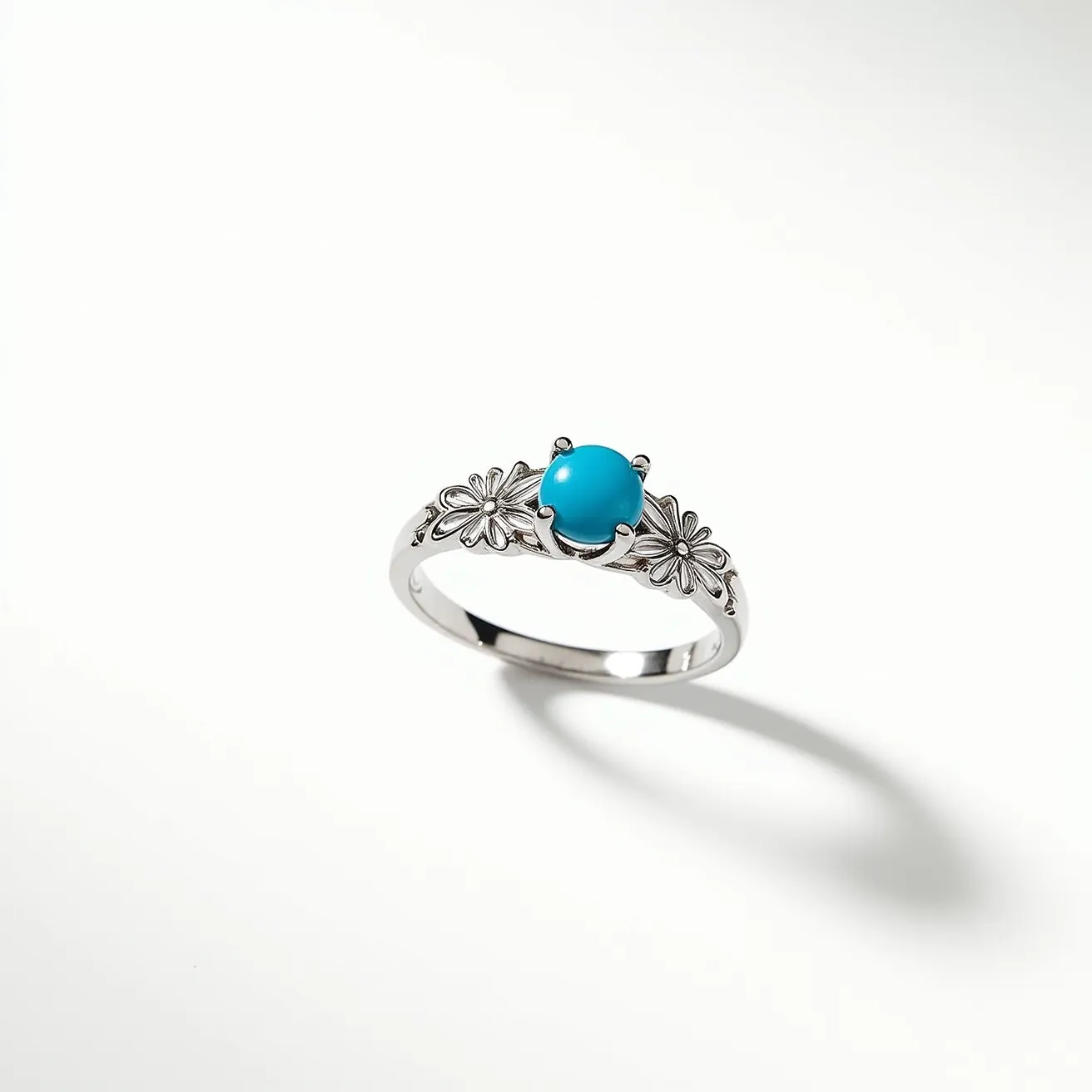 This December birthstone ring features a striking turquoise stone, which is traditionally associated with the month of December. The turquoise is smoothly polished and set in a bezel-style mounting that securely holds the gem. The band of the ring is made from a lustrous metal, possibly sterling silver, adorned with intricate floral engravings that enhance its elegant design. The ring's craftsmanship highlights the beauty of the turquoise while offering a refined and classic appearance.