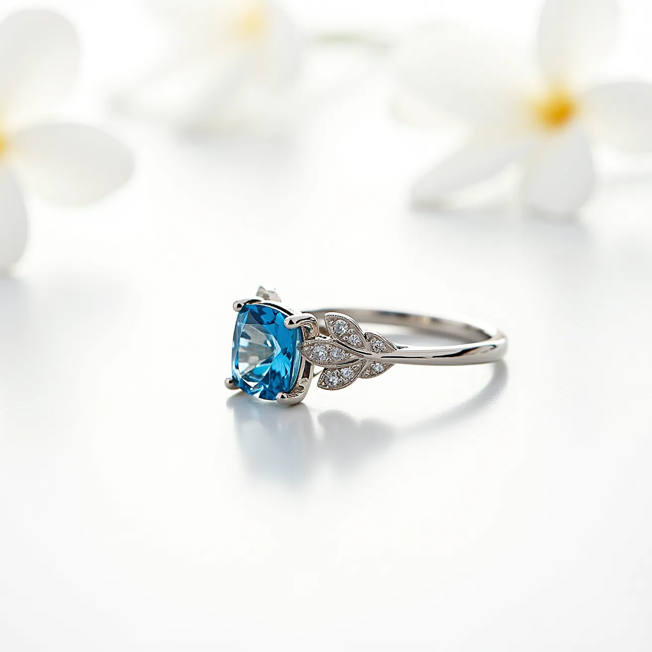 This December birthstone ring features a striking blue topaz gemstone, elegantly cut in a cushion shape that captures and reflects light beautifully. The centerpiece is securely held by a four-prong setting, adding stability and style. Complementing the central stone, the band showcases a delicate leaf design adorned with small, sparkling diamonds that enhance the ring's elegance. The band appears to be made of polished white gold or platinum, providing a sophisticated and modern look. This exquisite combination of design and materials makes it an ideal piece for admirers of December's stunning birthstone.