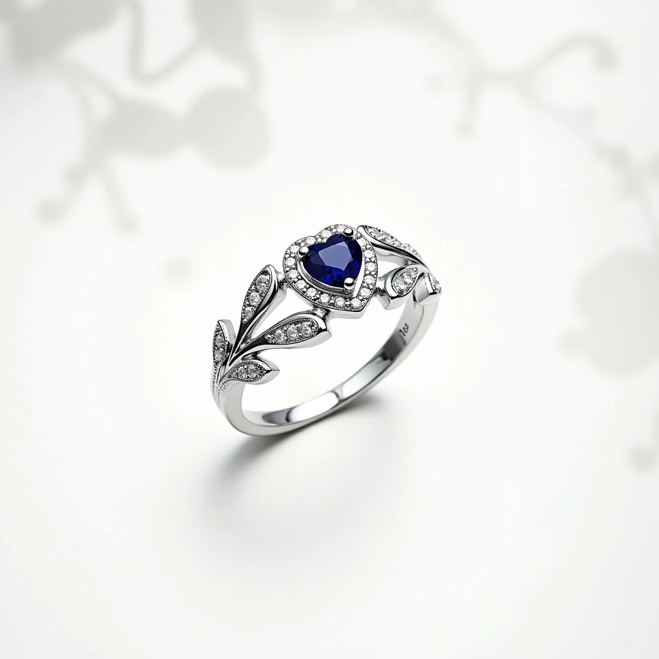 This diamond heart ring features a stunning heart-shaped blue gemstone at its center, likely a sapphire, set within a delicate halo of smaller round diamonds that enhance its brilliance. The band is crafted from a polished white metal, possibly white gold or platinum, and is adorned with intricate, vine-like designs that incorporate additional small diamonds. The elegant placement of the stones in a prong setting highlights the craftsmanship and attention to detail. The ring's seamless design creates a cohesive and harmonious piece, perfect for expressing elegance and sophistication.