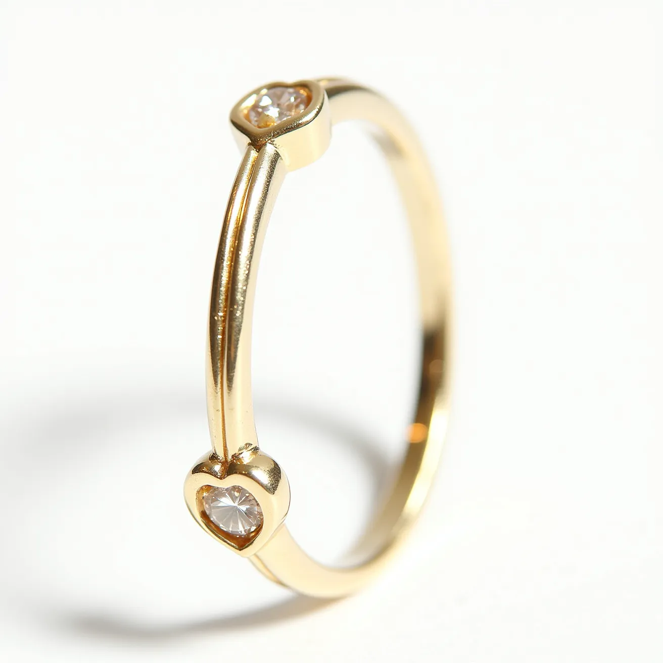 This diamond heart ring features a slender gold band adorned with two heart-shaped bezels, each housing a small round brilliant-cut diamond. The diamonds are securely set in the gold bezels, emphasizing the simplicity and elegance of the design. The use of gold as the primary material provides the ring with a classic and timeless appearance, while the heart-shaped bezels add a touch of romance and charm. The craftsmanship highlights the ring's delicate and graceful aesthetic, making it an ideal choice for those seeking a subtle yet sophisticated piece of jewelry.