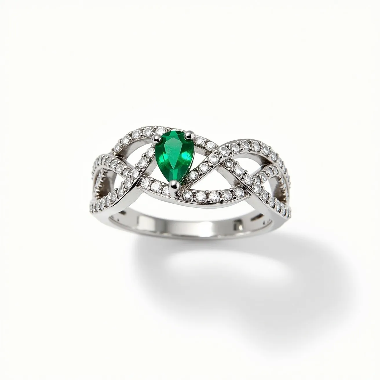 This diamond ring features a striking pear-cut green gemstone, likely an emerald, set in a prong setting at the center. The band is designed with an intricate infinity motif, encrusted with small round diamonds that accentuate the main gem. Crafted from a polished metal, possibly white gold or platinum, the ring showcases a harmonious blend of elegance and complexity without any visible clasps or attachments. The intertwining design and sparkling gems create a luxurious and sophisticated piece of jewelry.