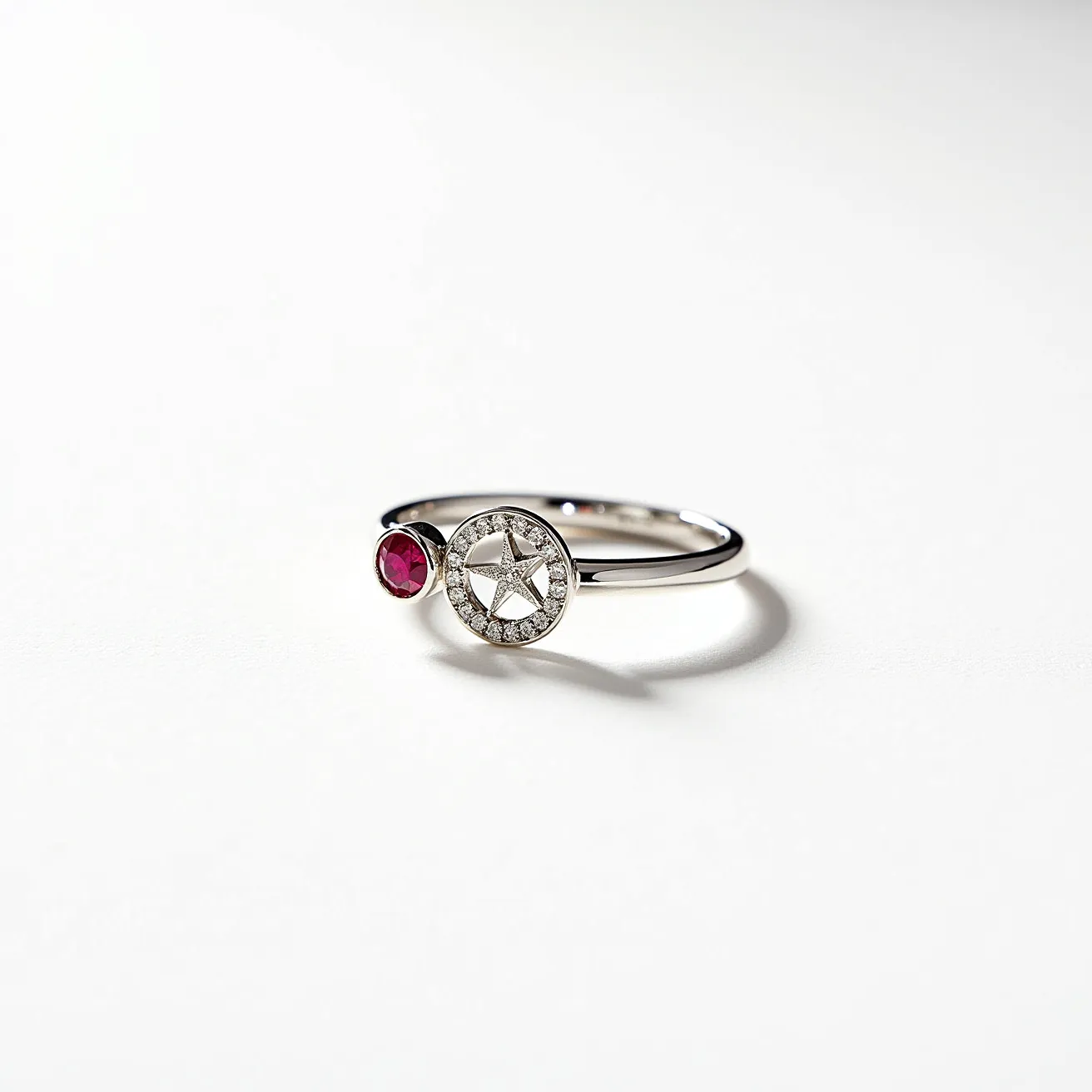 This diamond ring features a sleek metal band crafted from white gold. It showcases a notably unique design with two prominent elements: a round diamond-encrusted setting with a star motif at its center and a secondary round ruby embedded in a simple bezel setting. The star motif within the diamond setting adds a touch of whimsical elegance. The ruby provides a striking contrast to the shine of the diamonds, creating a lively interplay of colors. The ring is crafted without additional clasps, relying on its circular band for secure wear.