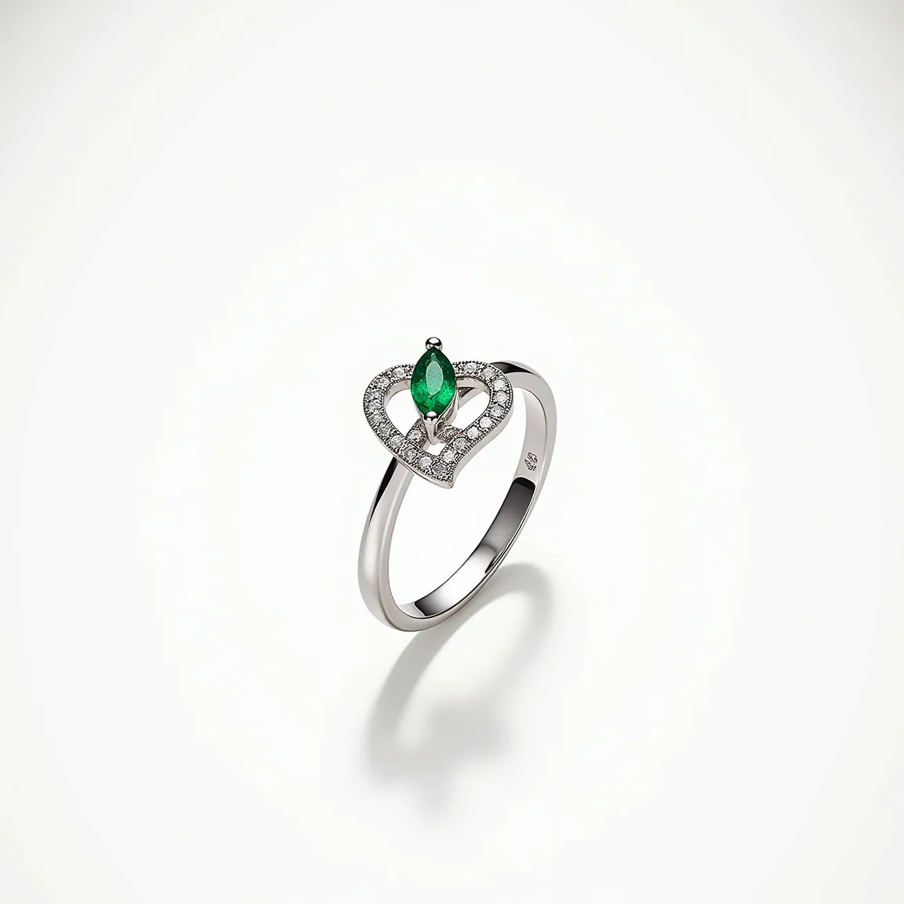 This diamond ring features a marquise-cut green gemstone, likely an emerald, set within the center of a heart-shaped design. The heart outline is adorned with a series of small, round diamonds, which add a sparkling accent to the piece. The band appears to be made of a polished metal, possibly white gold or platinum, complementing the overall elegant design. The setting secures the central gemstone with prongs, ensuring stability while maintaining the ring’s sophisticated aesthetic.