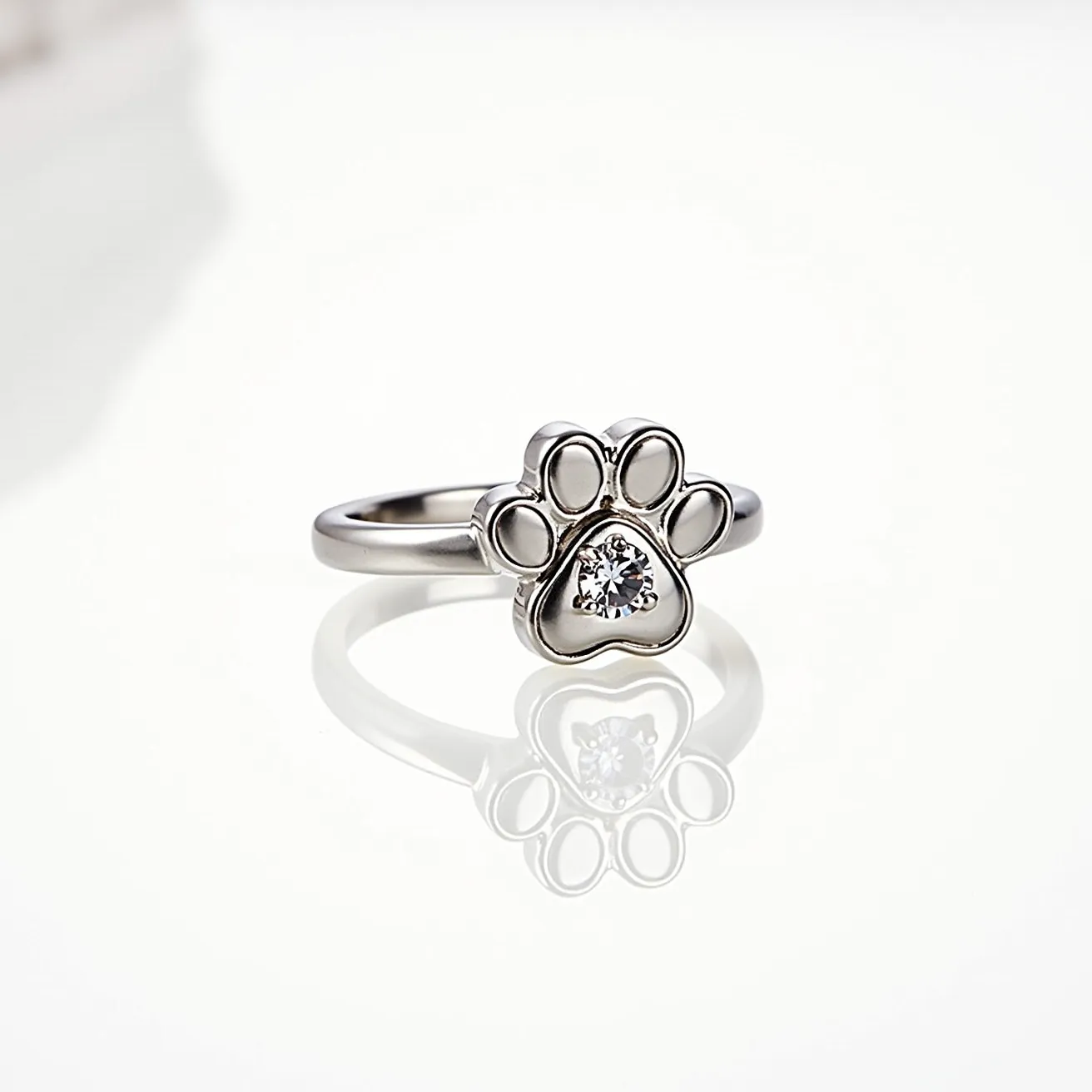 This dog ring features a charming paw design crafted from a shiny metal, possibly sterling silver or white gold, which gives it a sleek appearance. The paw's center is adorned with a single, brilliant-cut gemstone, likely a diamond or a high-quality cubic zirconia, set securely in a bezel setting. This ring does not appear to have any clasps or additional attachments, focusing instead on the simplicity and elegance of the paw motif and the sparkling stone.