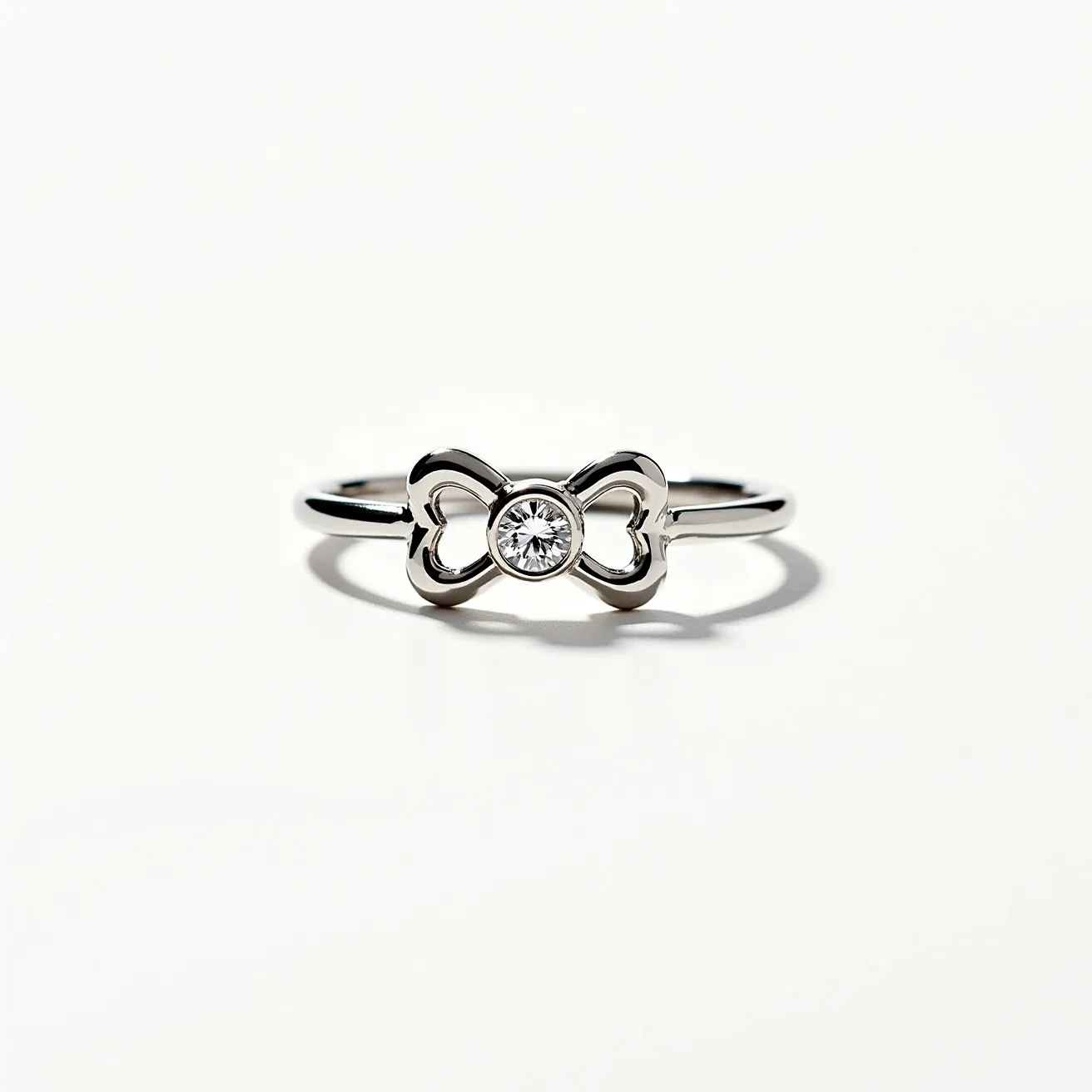 This dog ring features a sleek metal band, possibly made of silver or white gold, elegantly shaped into a bow motif. At the center of the bow sits a round-cut gemstone, likely a diamond, securely set in a bezel setting which adds a classic touch to the design. The simplicity and elegance of the ring make it a charming accessory, with the bow adding a playful element suitable for dog lovers.