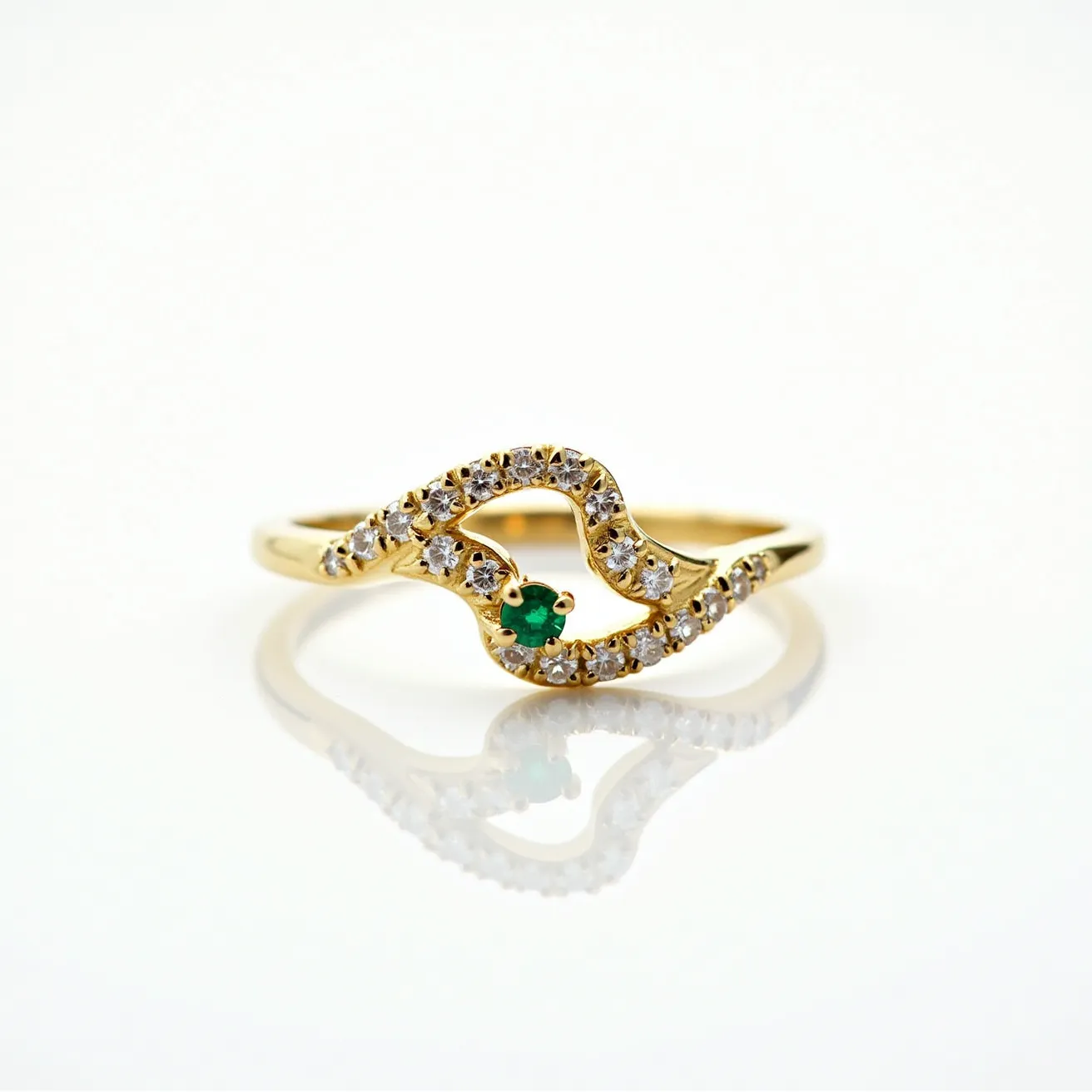 This emerald ring features a striking design centered around a vivid, round-cut emerald gemstone, held securely in a prong setting. The band is crafted from gold and showcases intricate detailing along its curvature, adorned with numerous small, round-cut diamonds that are set in a pave style. The diamonds add a brilliant sparkle, complementing the deep green of the emerald. The overall design is elegant, with the materials and craftsmanship highlighting the luxurious nature of the ring.