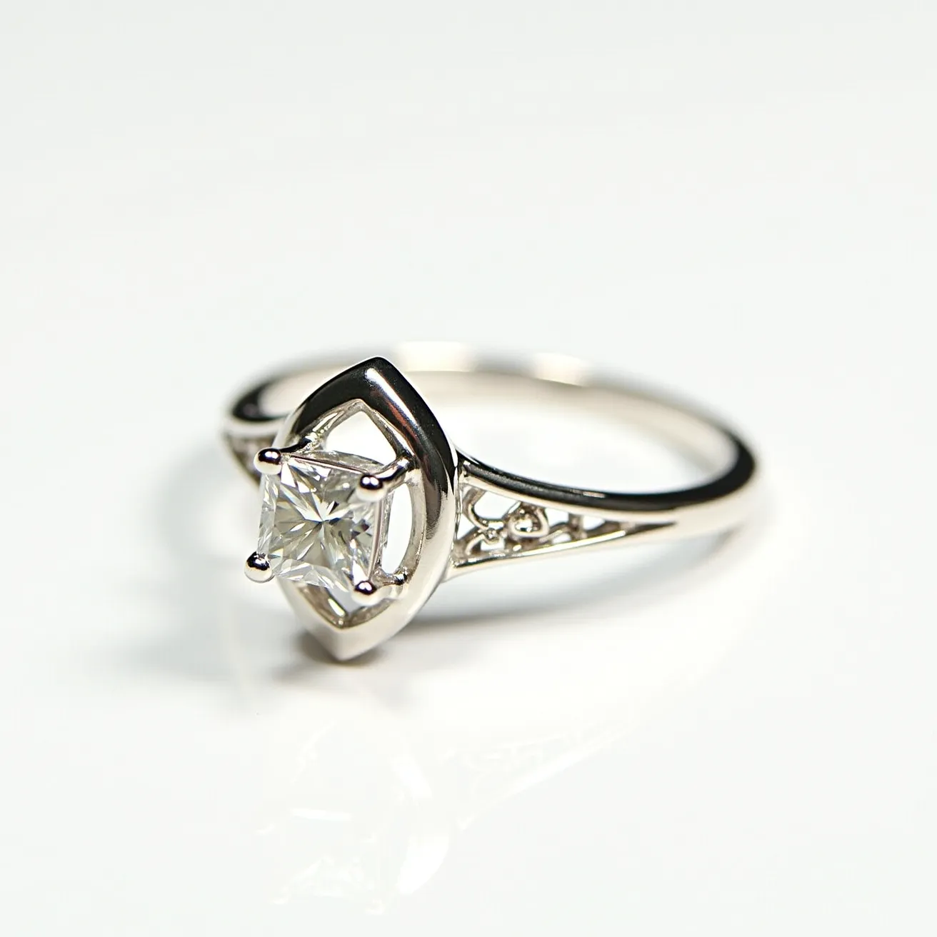 This engagement ring features a central square diamond, likely a princess cut, set in a four-prong setting. The ring band is made of a silver-toned metal, possibly white gold or platinum, with delicate filigree details on either side of the stone, adding a touch of elegance. The overall design combines modern simplicity with intricate detailing, providing a sophisticated and timeless look.