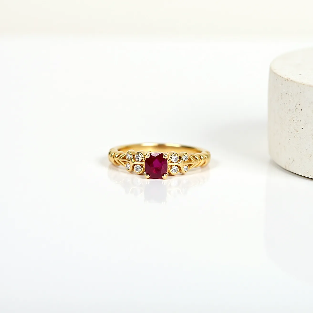 This engraved ring features a beautifully set ruby at its center, cut into a faceted shape to enhance its deep red hue. The ruby is elegantly flanked by smaller brilliant-cut diamonds, which are securely held in place by prong settings, adding a touch of sparkle to the design. The band itself is crafted from a warm yellow gold, showcasing intricate engravings along its sides that add texture and visual interest to the piece. The combination of the vibrant ruby and the delicate diamonds, set in luxurious gold, gives the ring a classic and refined appearance.