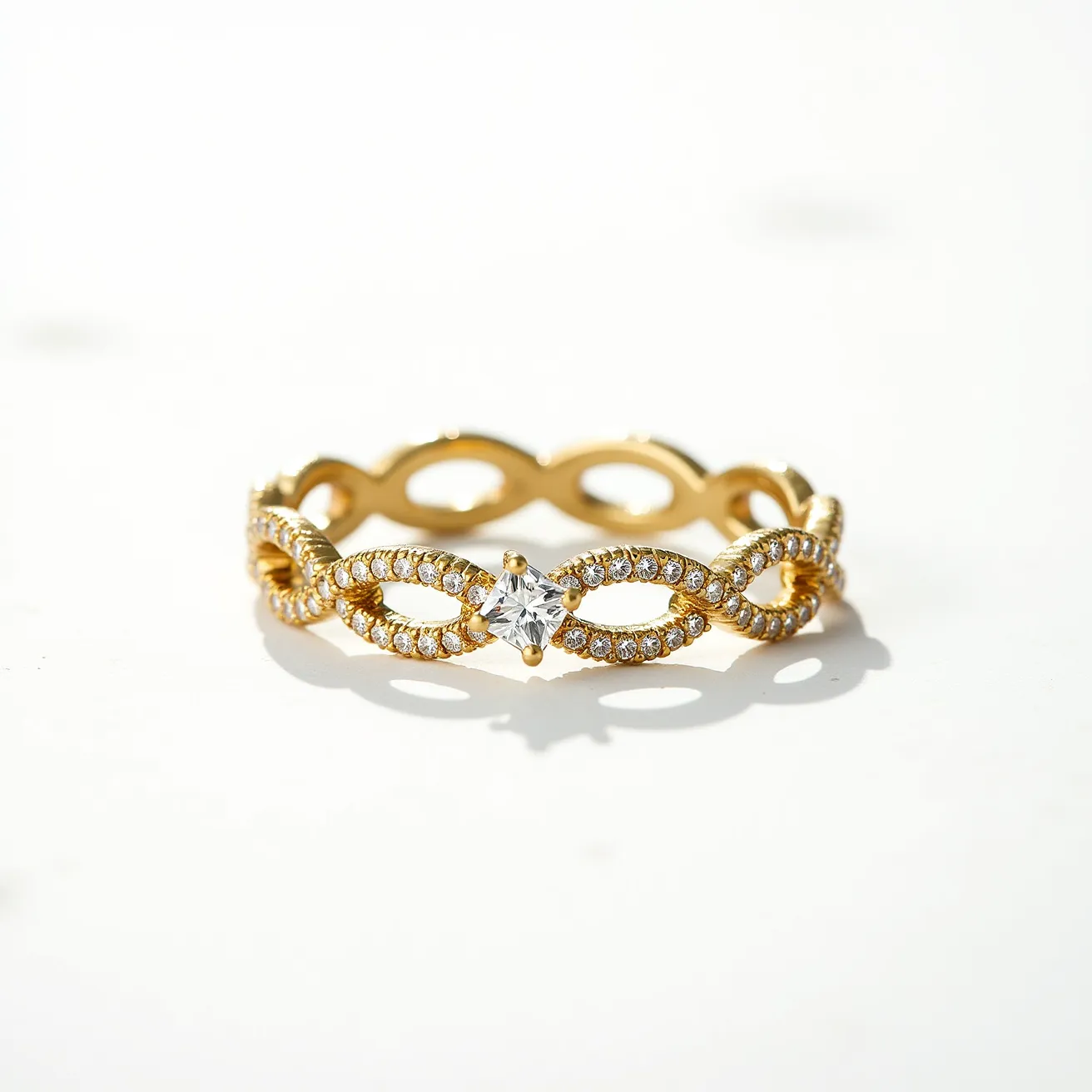 This eternity band ring features a delicate interlocking design crafted from gold, with a series of small round-cut diamonds meticulously set in a pave arrangement along its surface. At the center of the infinity loop pattern, a prominent marquise-cut diamond is elegantly mounted in a prong setting, serving as a striking focal point. The continuous loop of the band showcases the seamless integration of materials and craftsmanship.