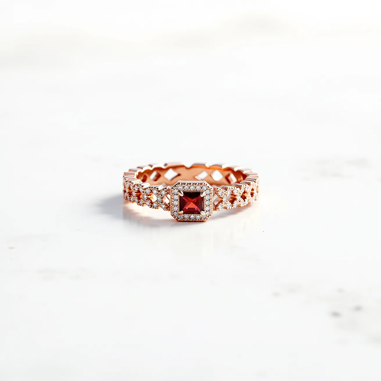 This eternity ring features a band crafted from rose gold, showcasing a central square-cut red gemstone, likely a garnet, held in a prong setting. The band is intricately designed with alternating rows of small, round diamonds that are also prong-set, adding a continuous sparkle around the entirety of the ring. The design is characterized by a seamless loop, with no visible clasp or attachment, emphasizing its eternal symbolism.