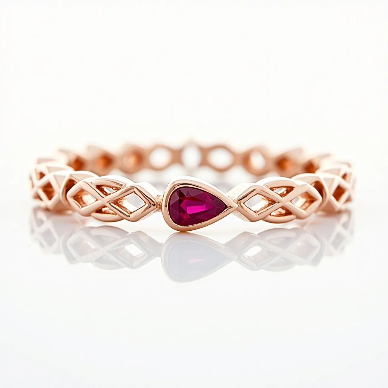 This eternity ring features a rose gold band with an intricate lattice design. The centerpiece is a pear-shaped ruby, set in a bezel-style setting, which enhances the vibrancy of the red gemstone. The lattice pattern continues around the band, creating a consistent and elegant look without a clasp or closure, as is typical for eternity rings. The combination of the rose gold metal and the red hue of the ruby offers a luxurious and timeless aesthetic.